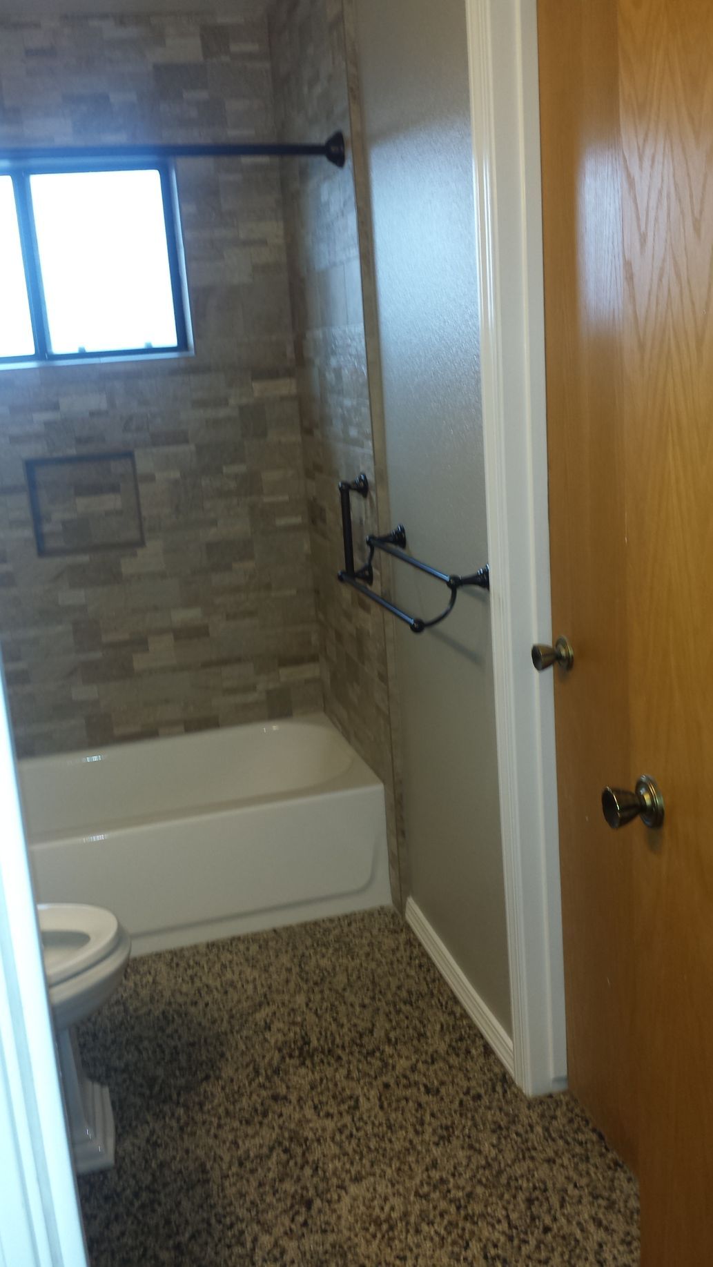 A bathroom with a toilet , bathtub , and window.