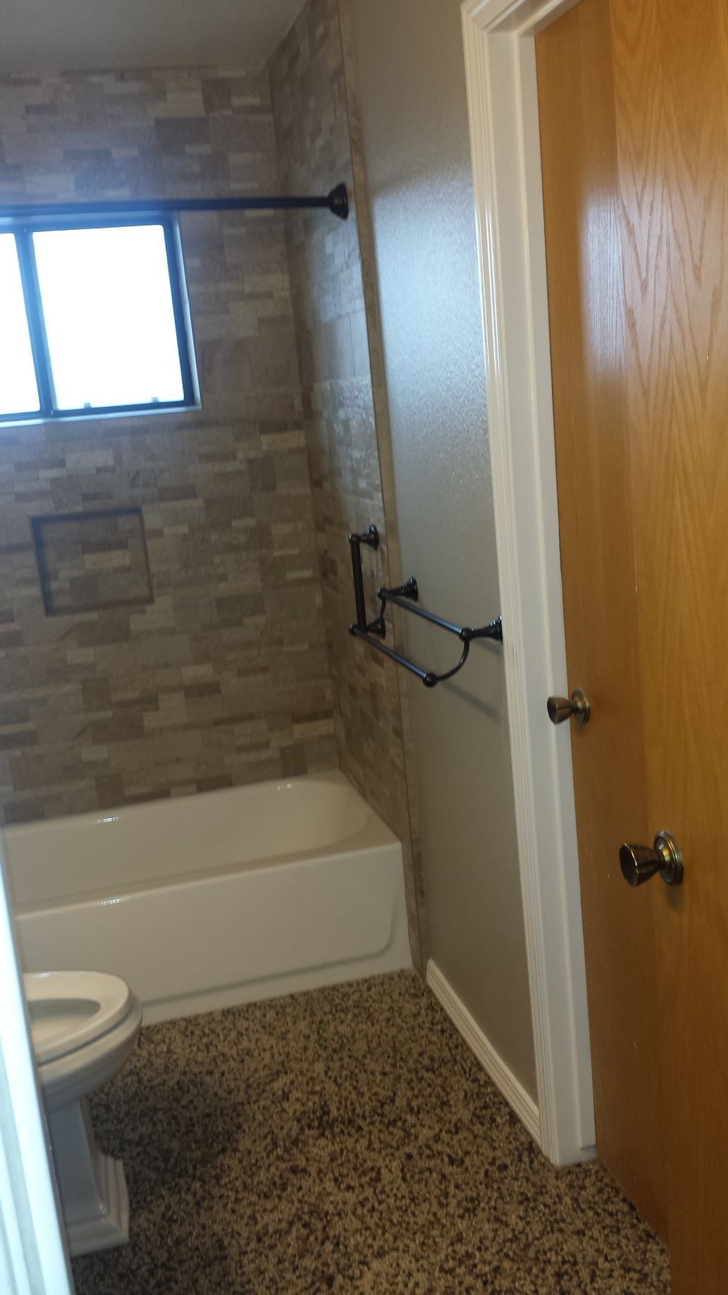 A bathroom with a toilet , tub , shower and window.