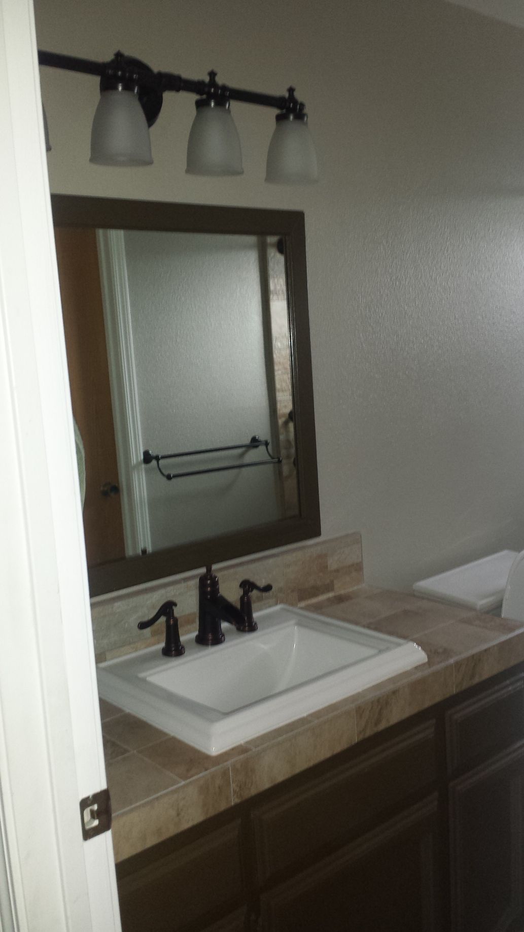A bathroom with a sink , mirror and light fixture.