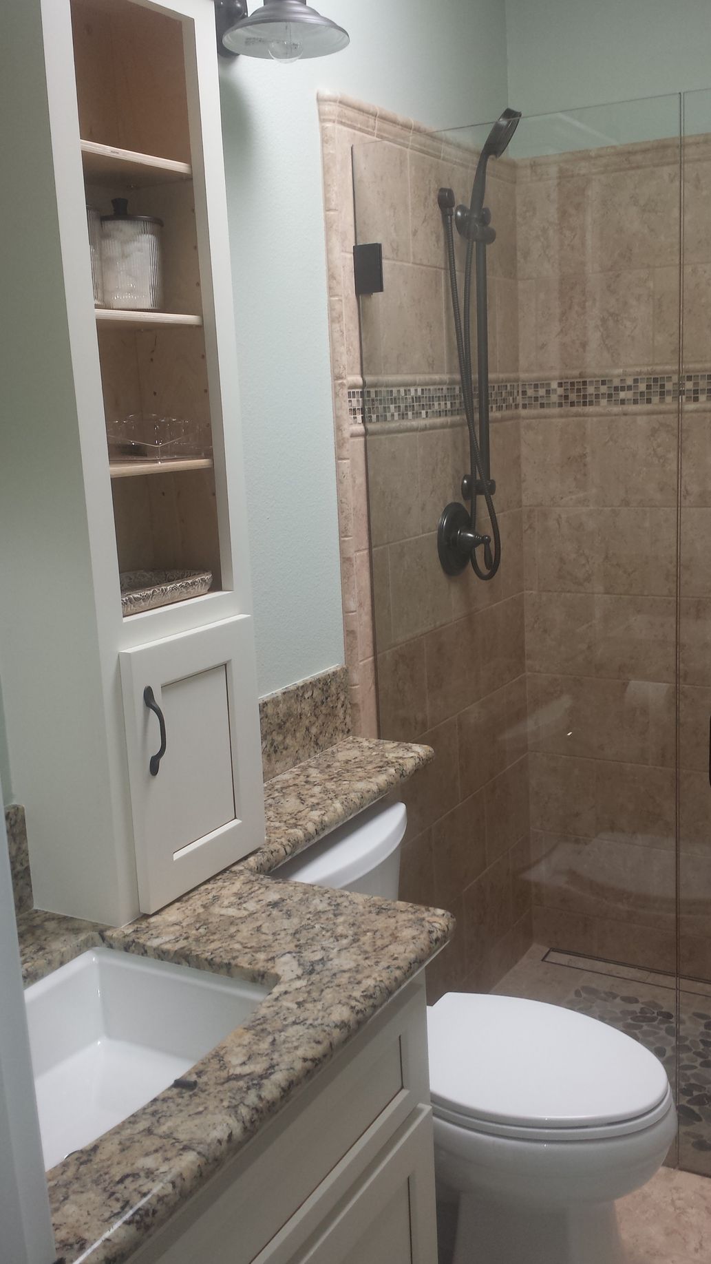 A bathroom with a toilet , sink and shower.