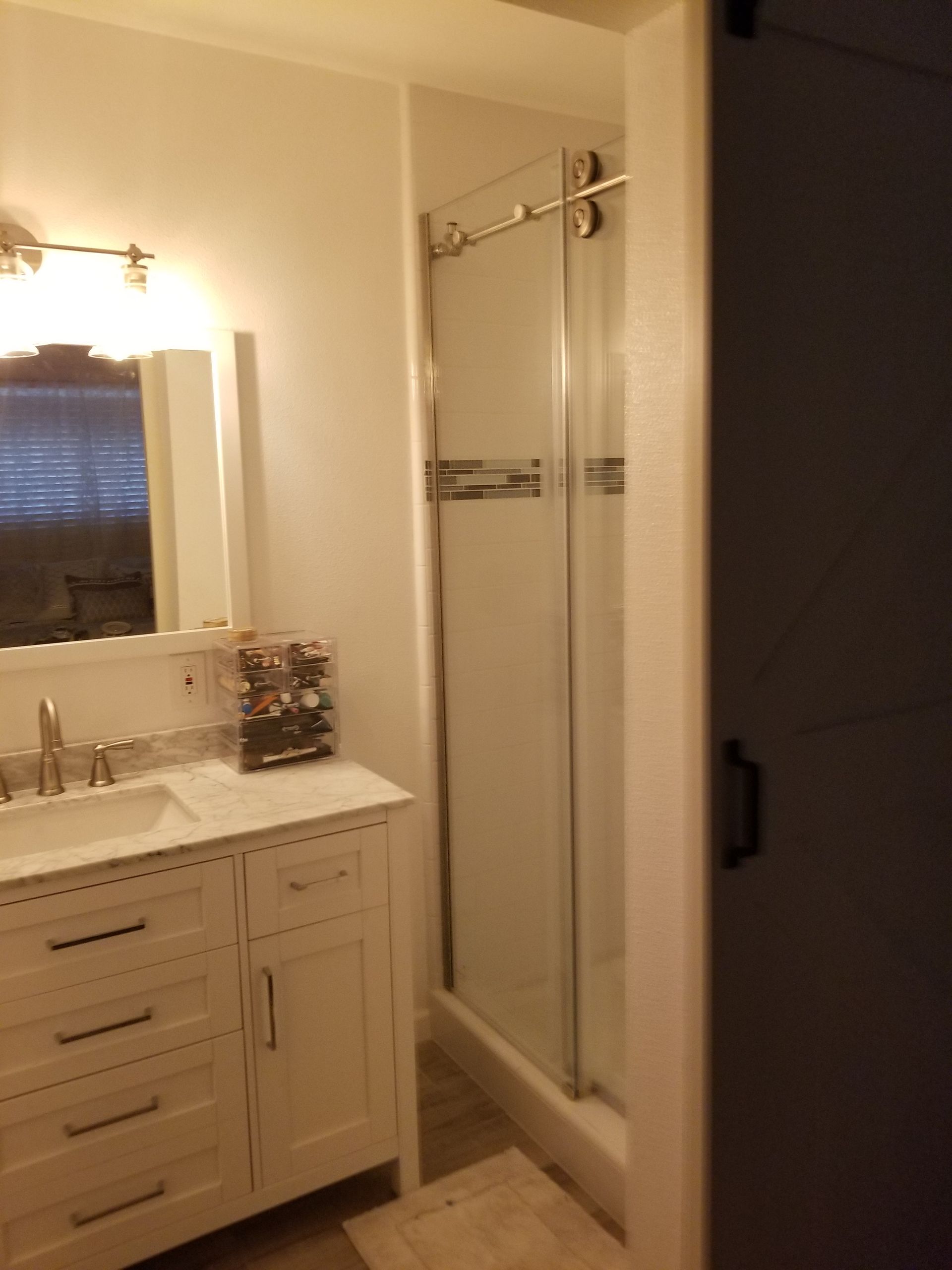 A bathroom with a sink , mirror , and shower stall.