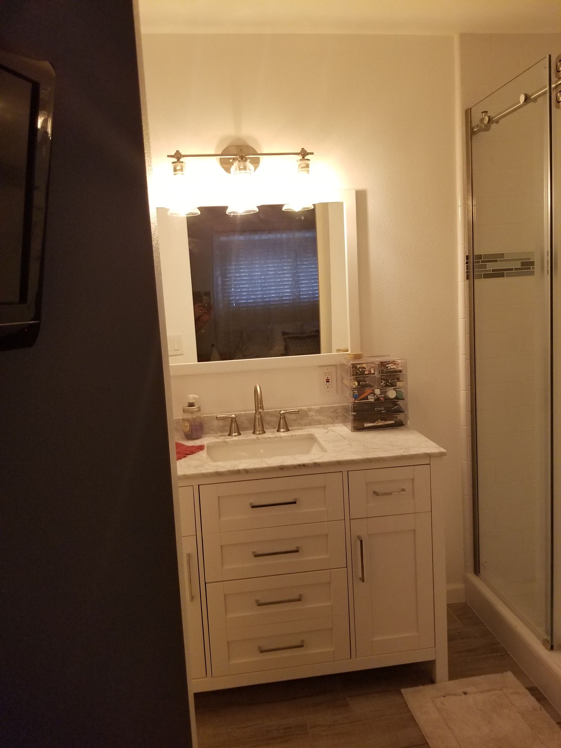 A bathroom with a sink a mirror and a walk in shower