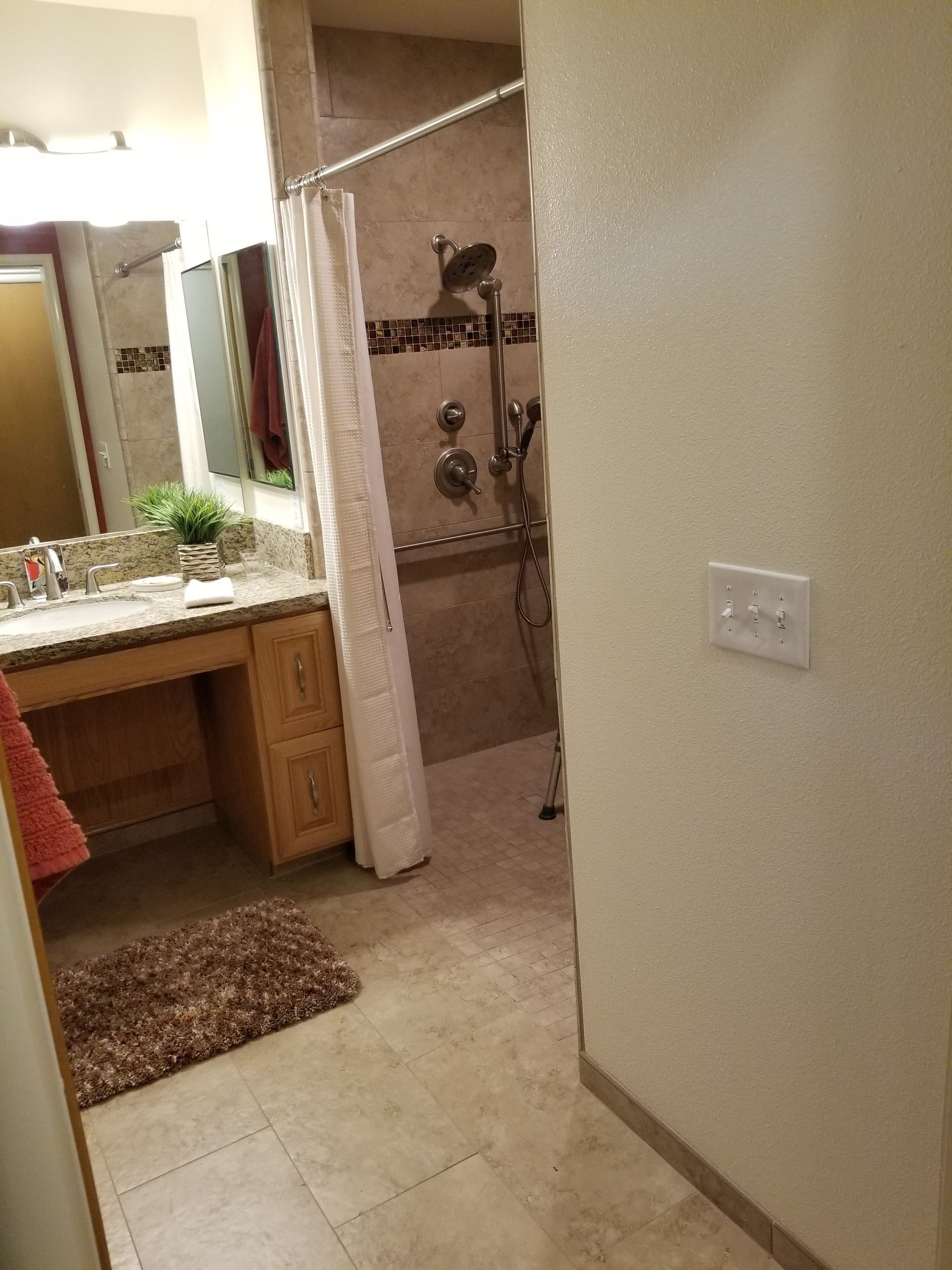 A bathroom with a walk in shower and a sink