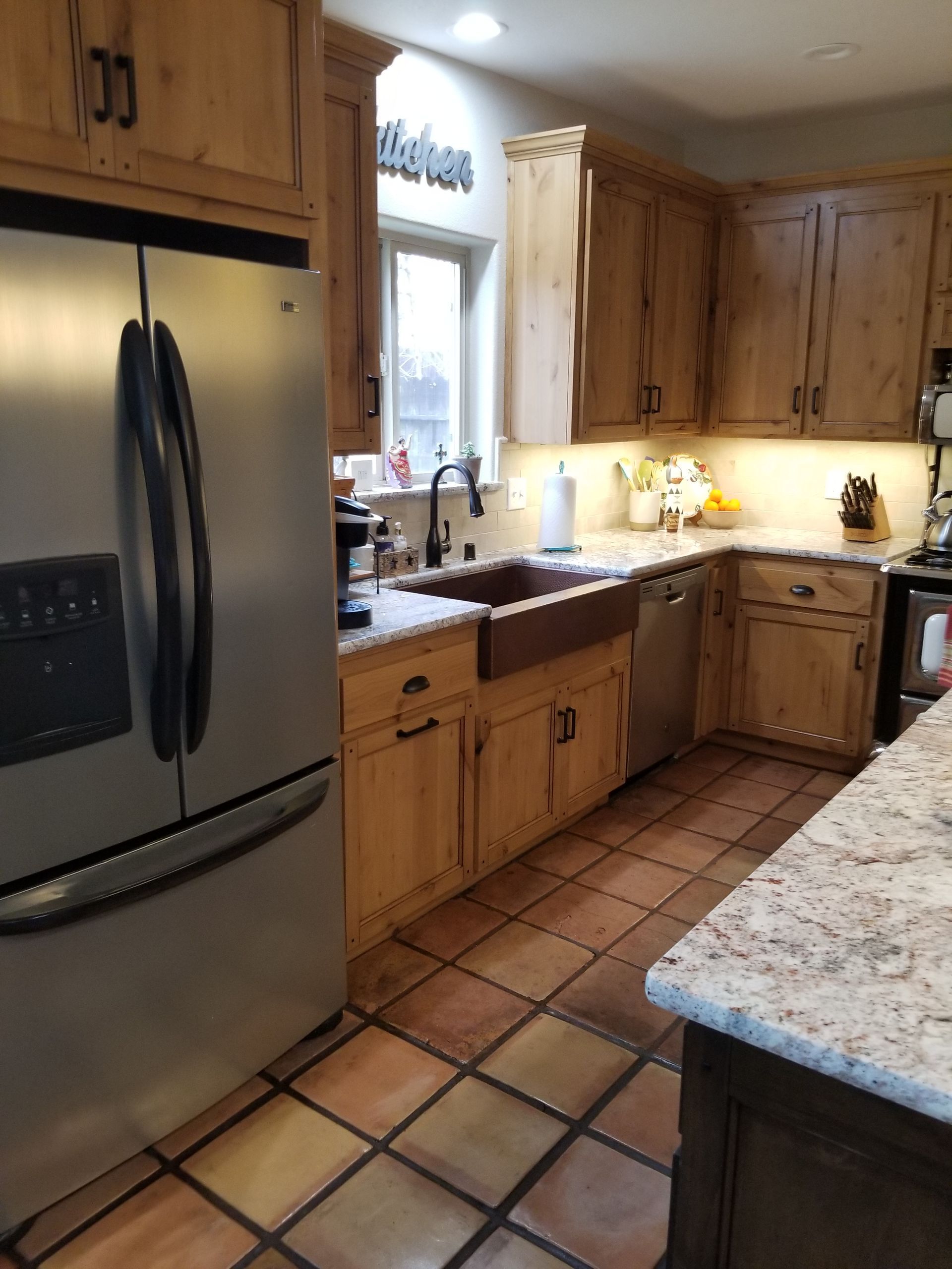A kitchen with wooden cabinets and a stainless steel refrigerator