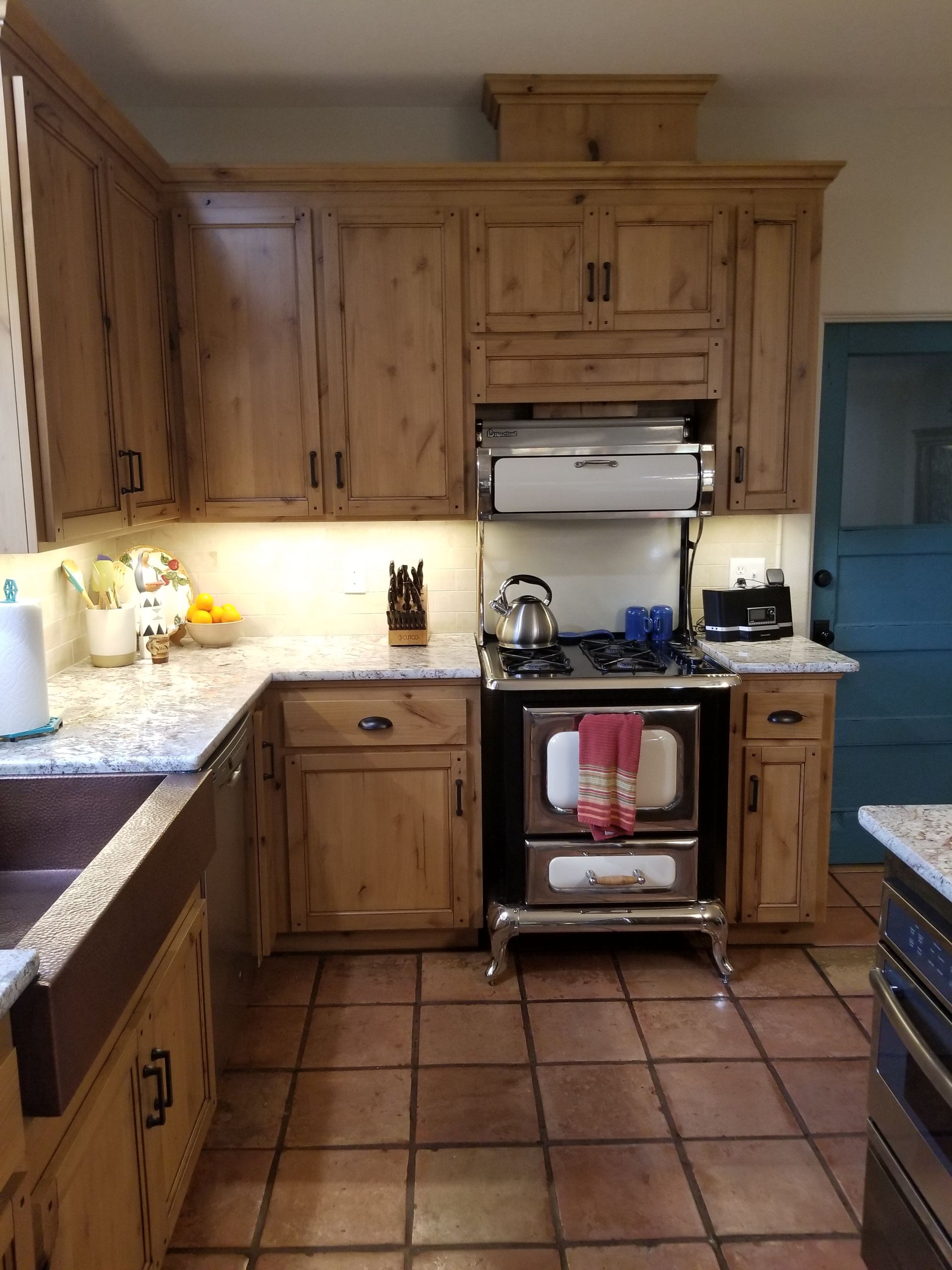 A kitchen with wooden cabinets a stove and a sink