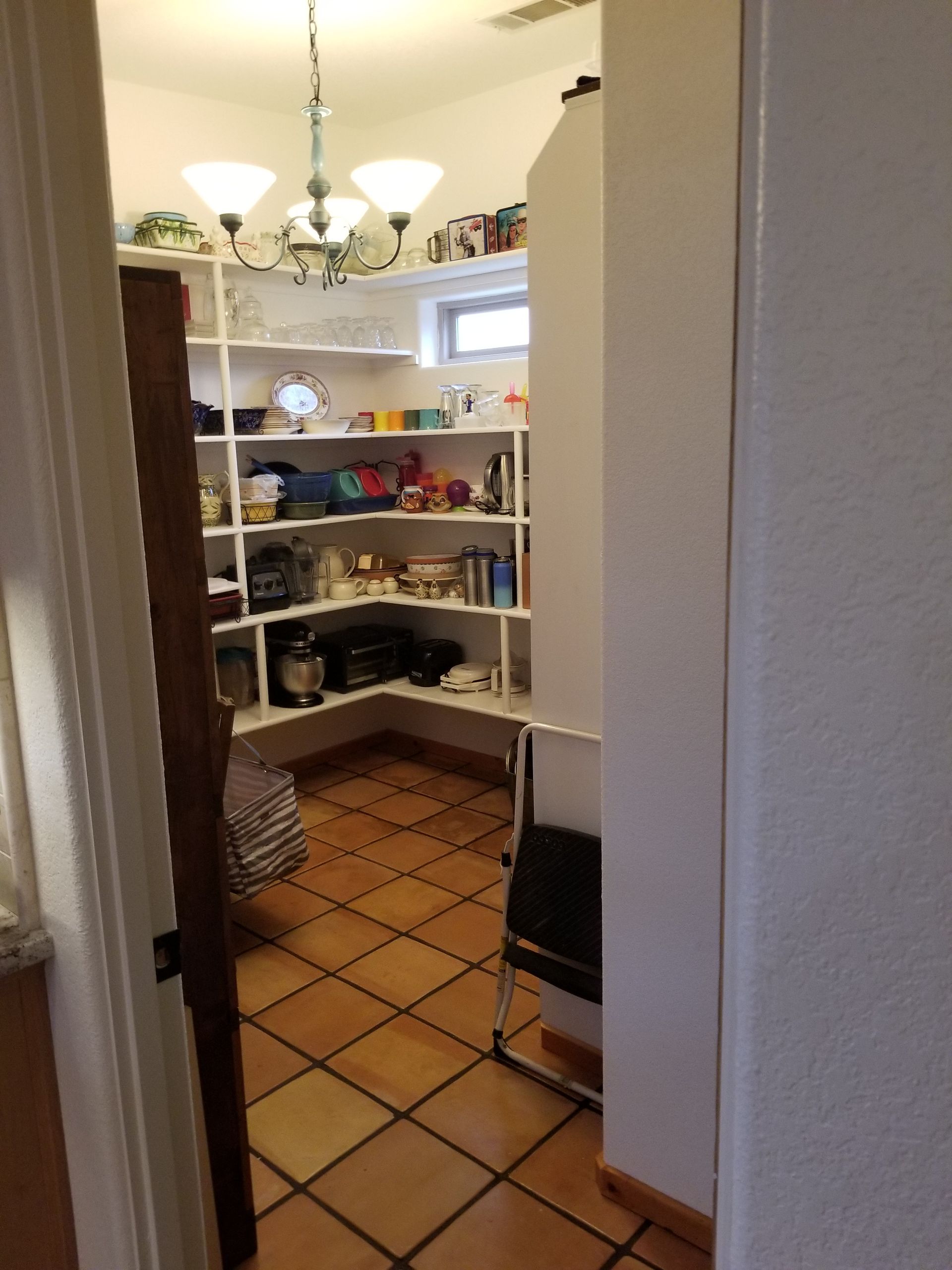 A pantry with a tiled floor and shelves filled with various items