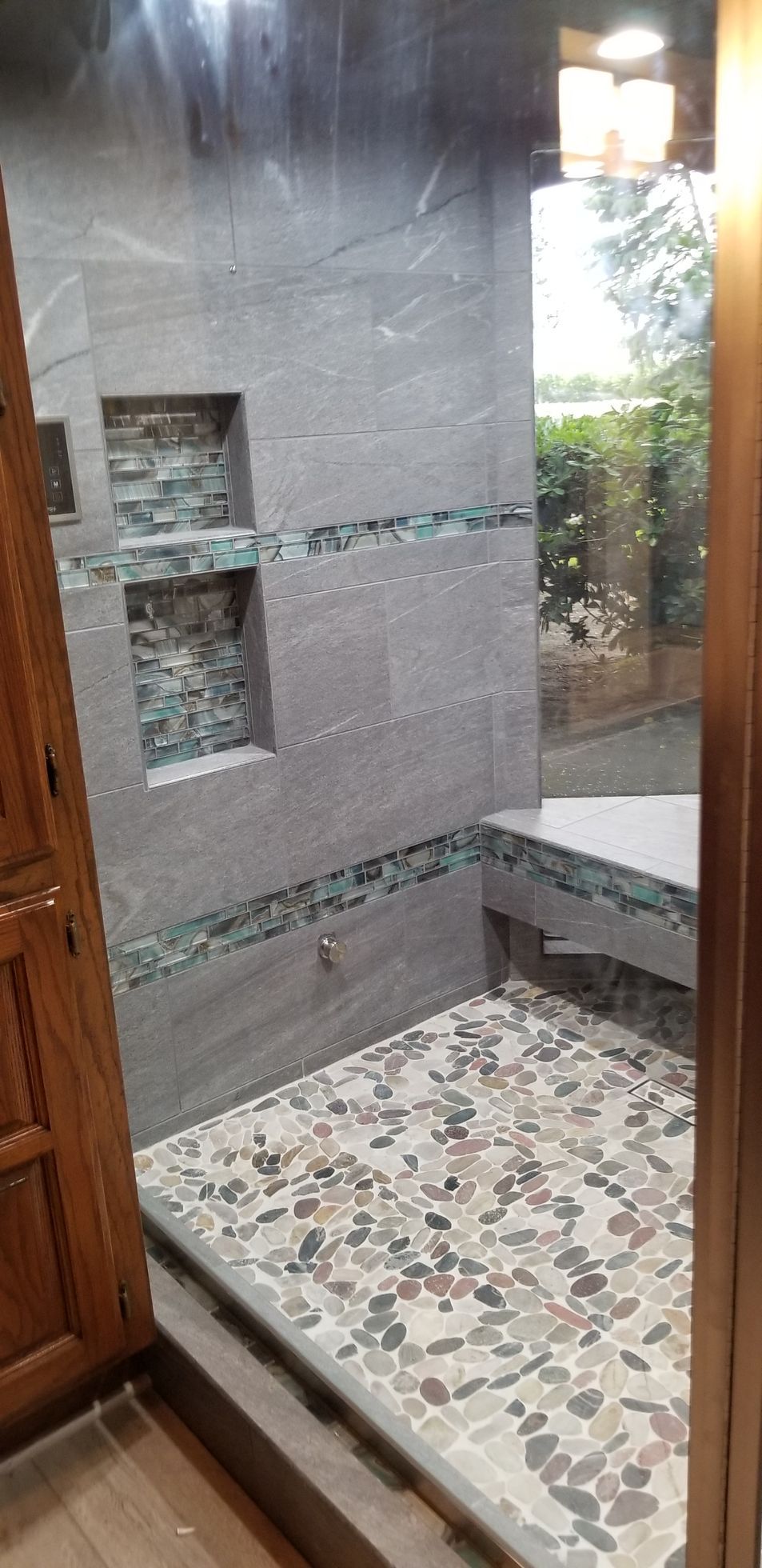 A bathroom with a walk in shower and a bench.
