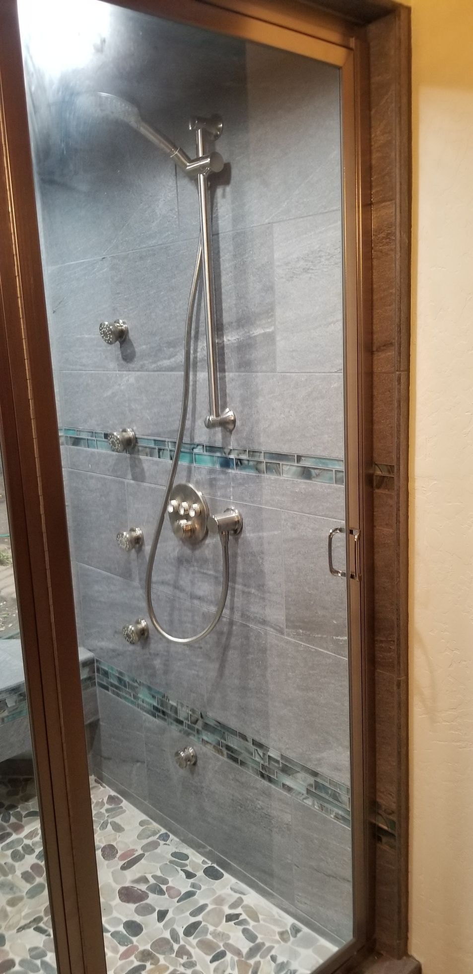 A bathroom with a walk in shower and a glass door.