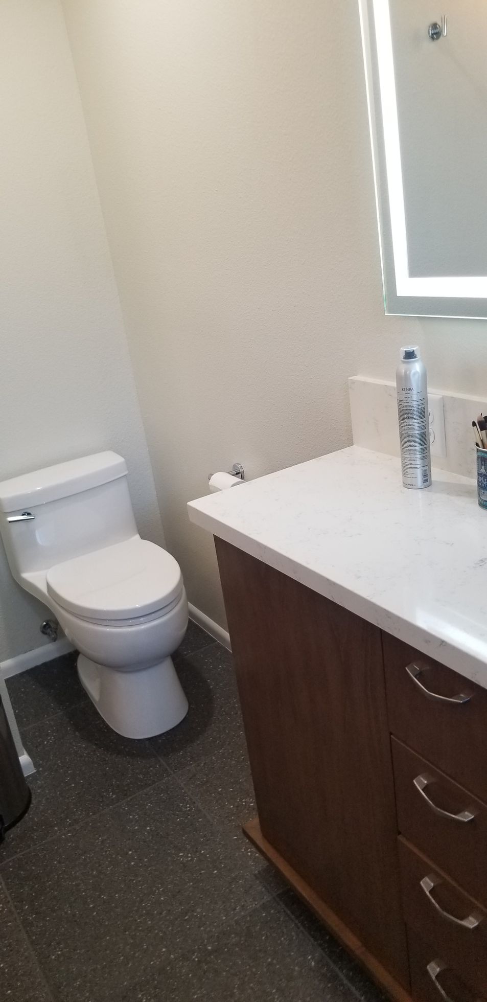 A bathroom with a toilet , sink and mirror.