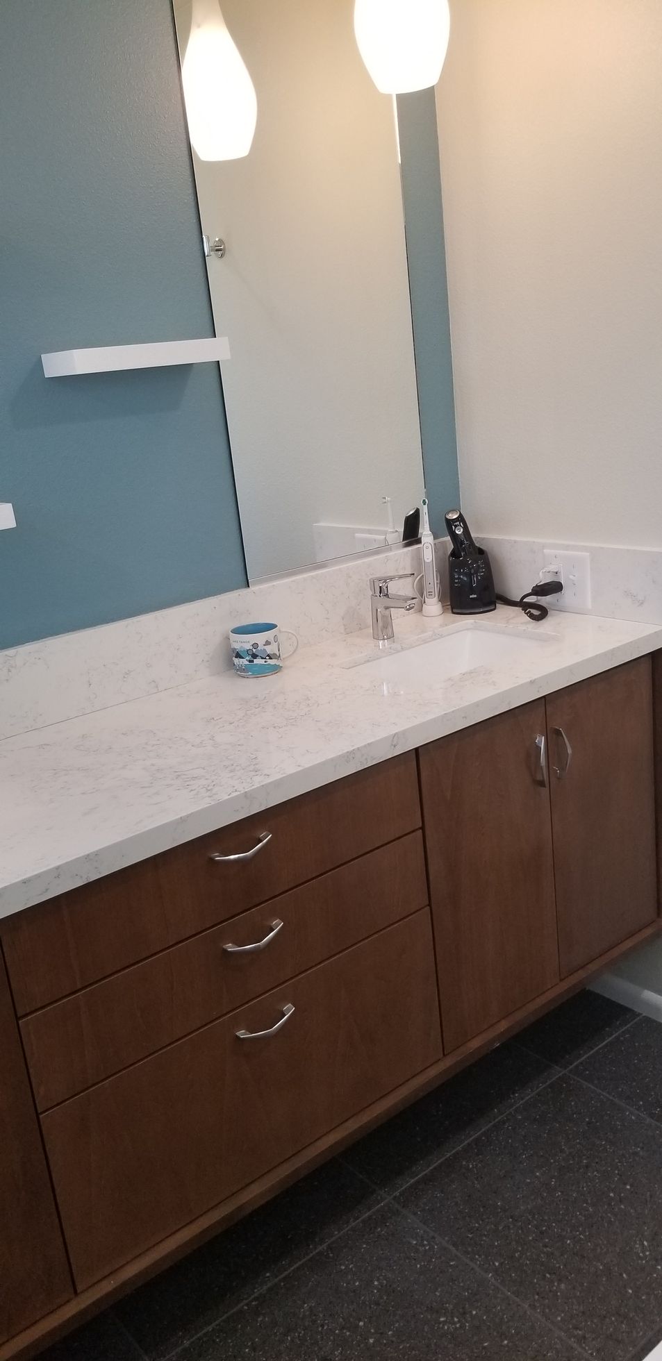 A bathroom with a sink , mirror and drawers.