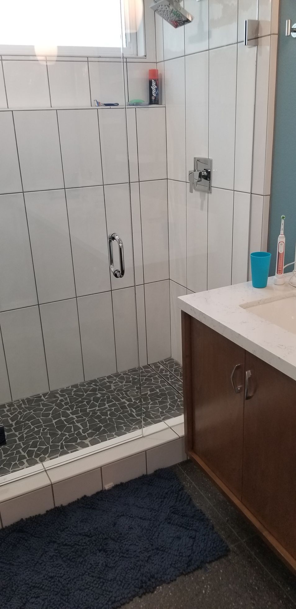 A bathroom with a walk in shower , sink , and mirror.