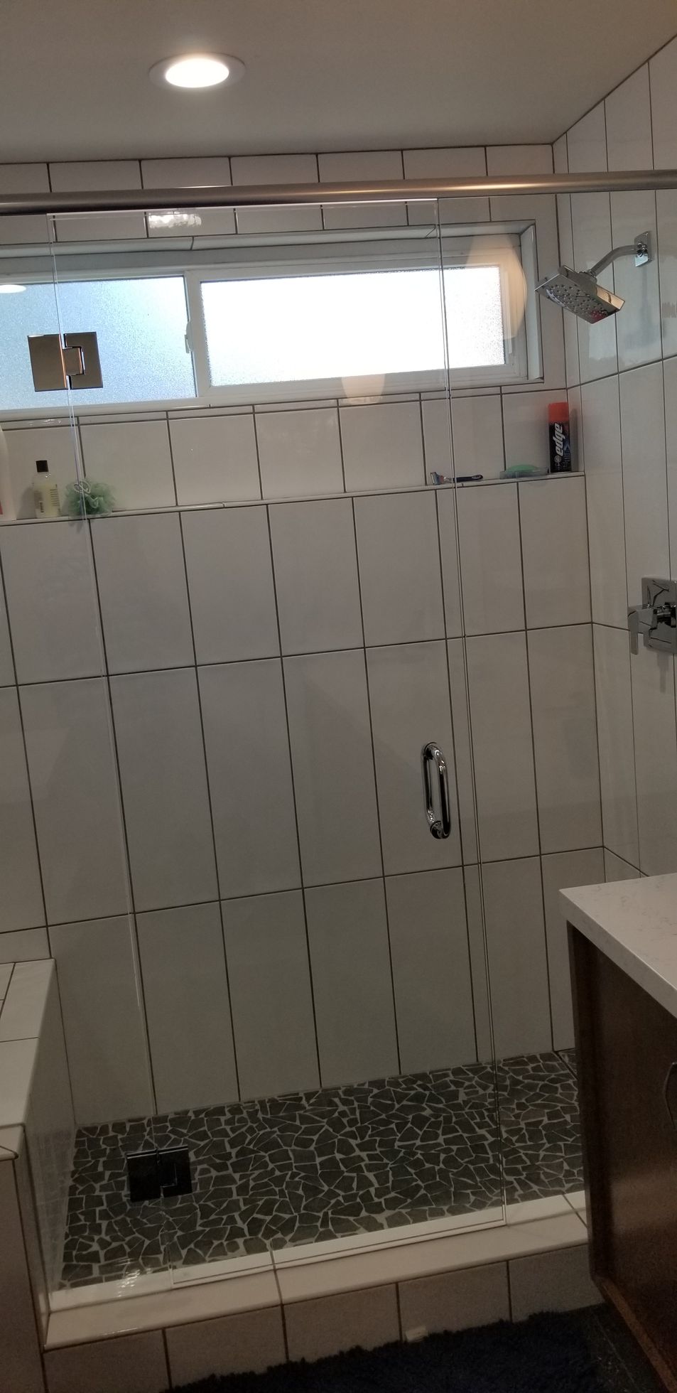 A bathroom with a walk in shower and a window.