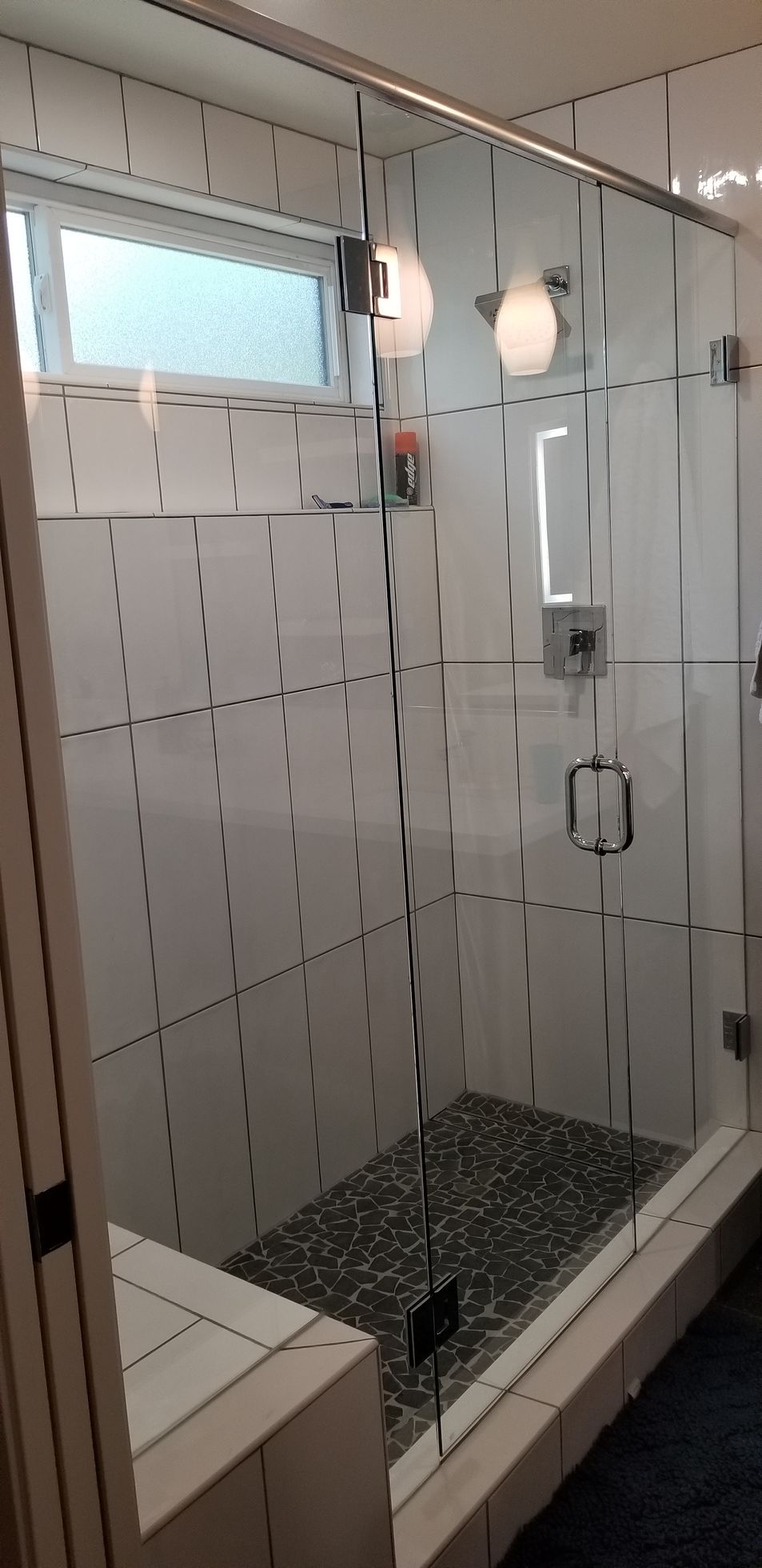 A bathroom with a walk in shower with a glass door.