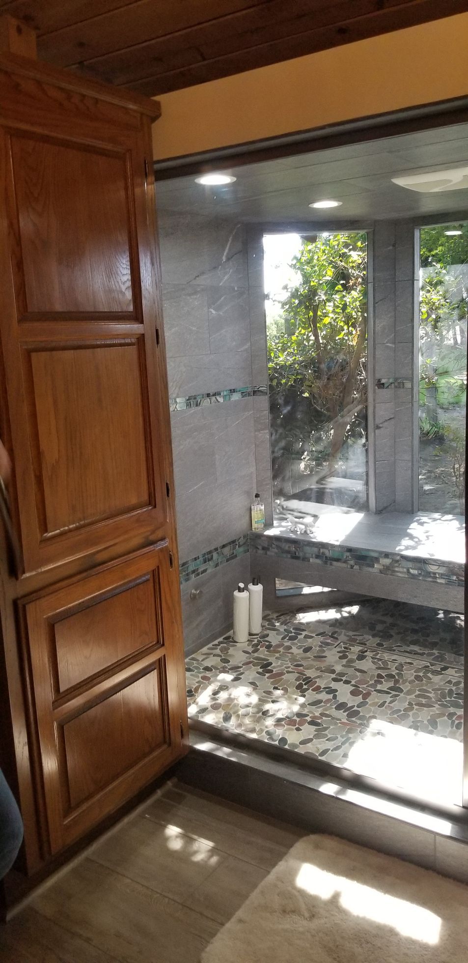 A bathroom with a walk in shower and a large window.