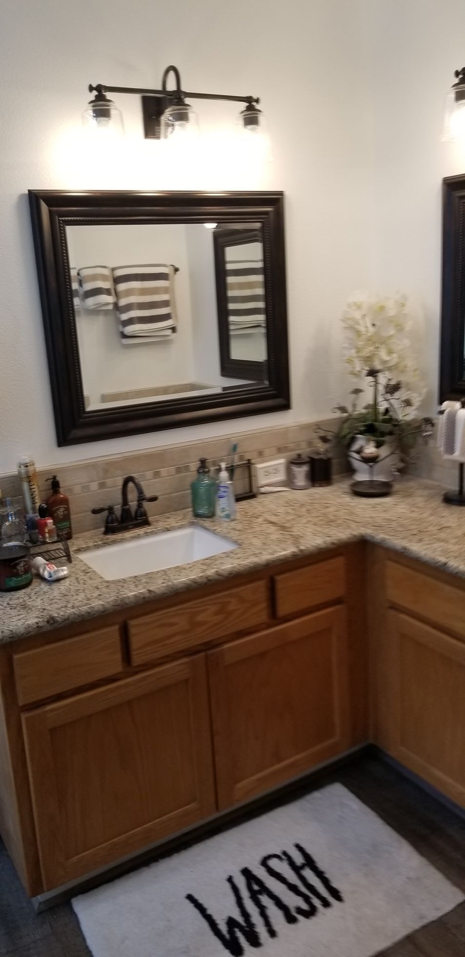 A bathroom with a sink , mirror and a rug that says `` wash ''.