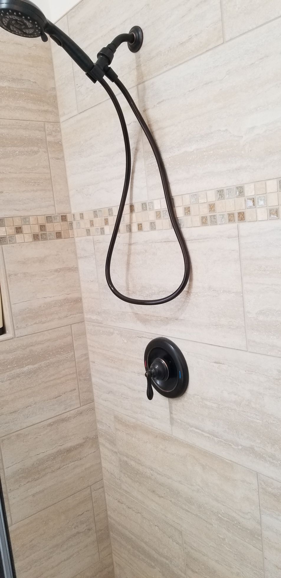 A black shower head is hanging from a tiled wall in a bathroom.