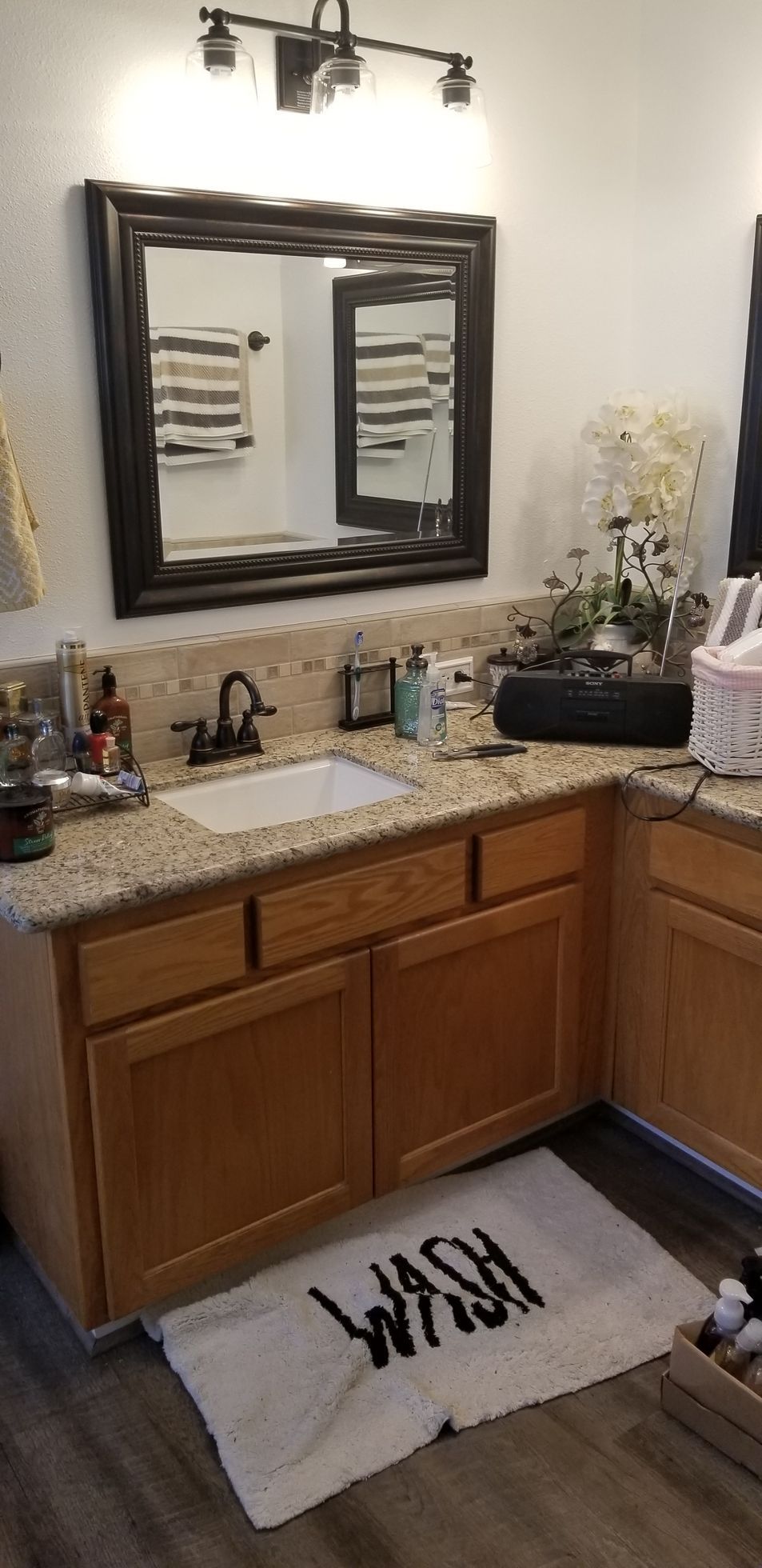 A bathroom with a sink , mirror , cabinets and a rug.