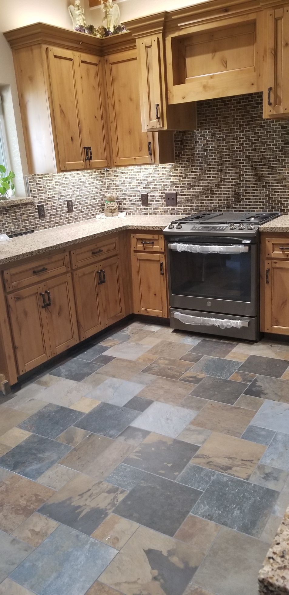 A kitchen with wooden cabinets , stainless steel appliances , and a tile floor.