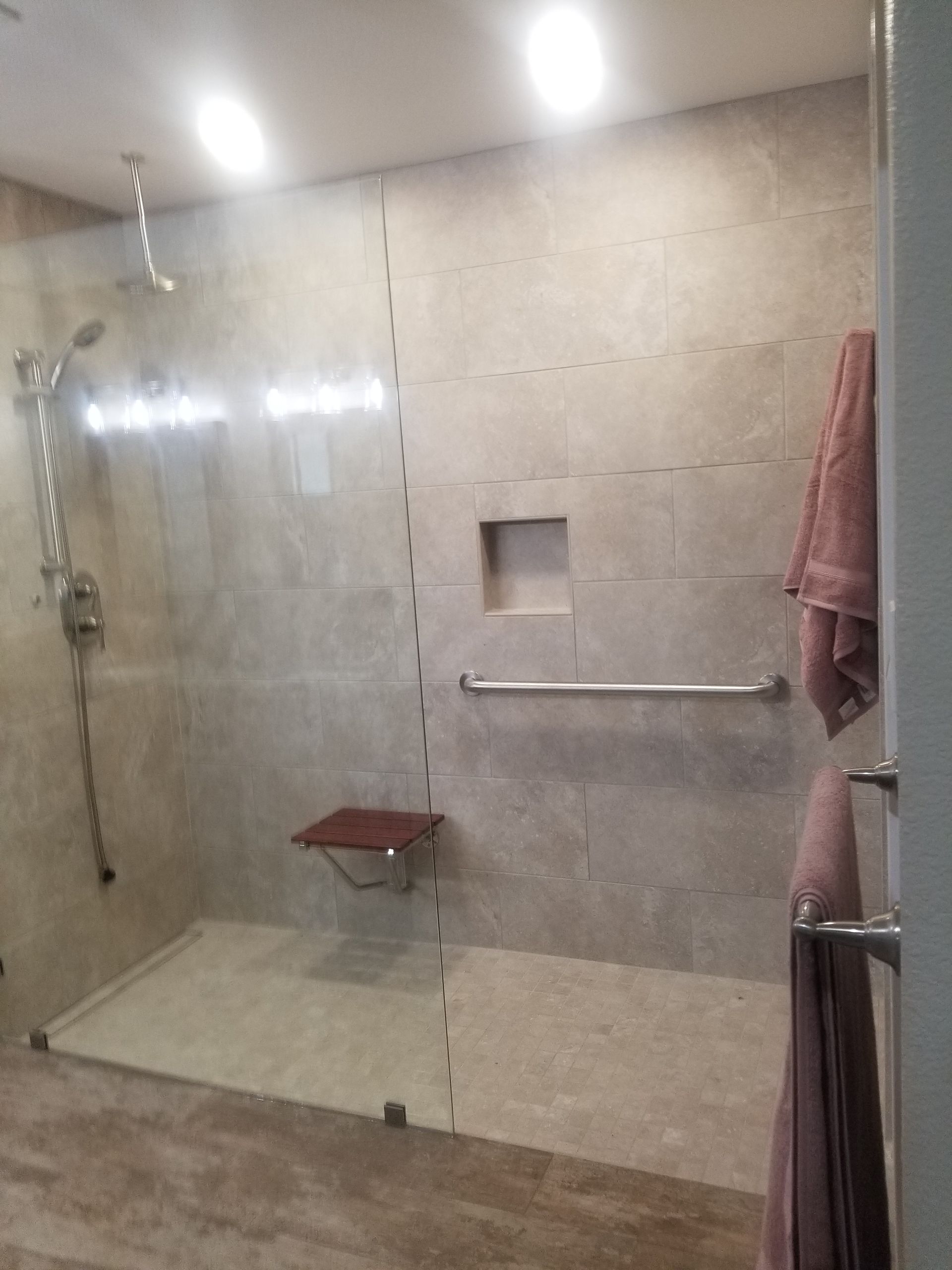 A bathroom with a walk in shower and a towel hanging on the wall.
