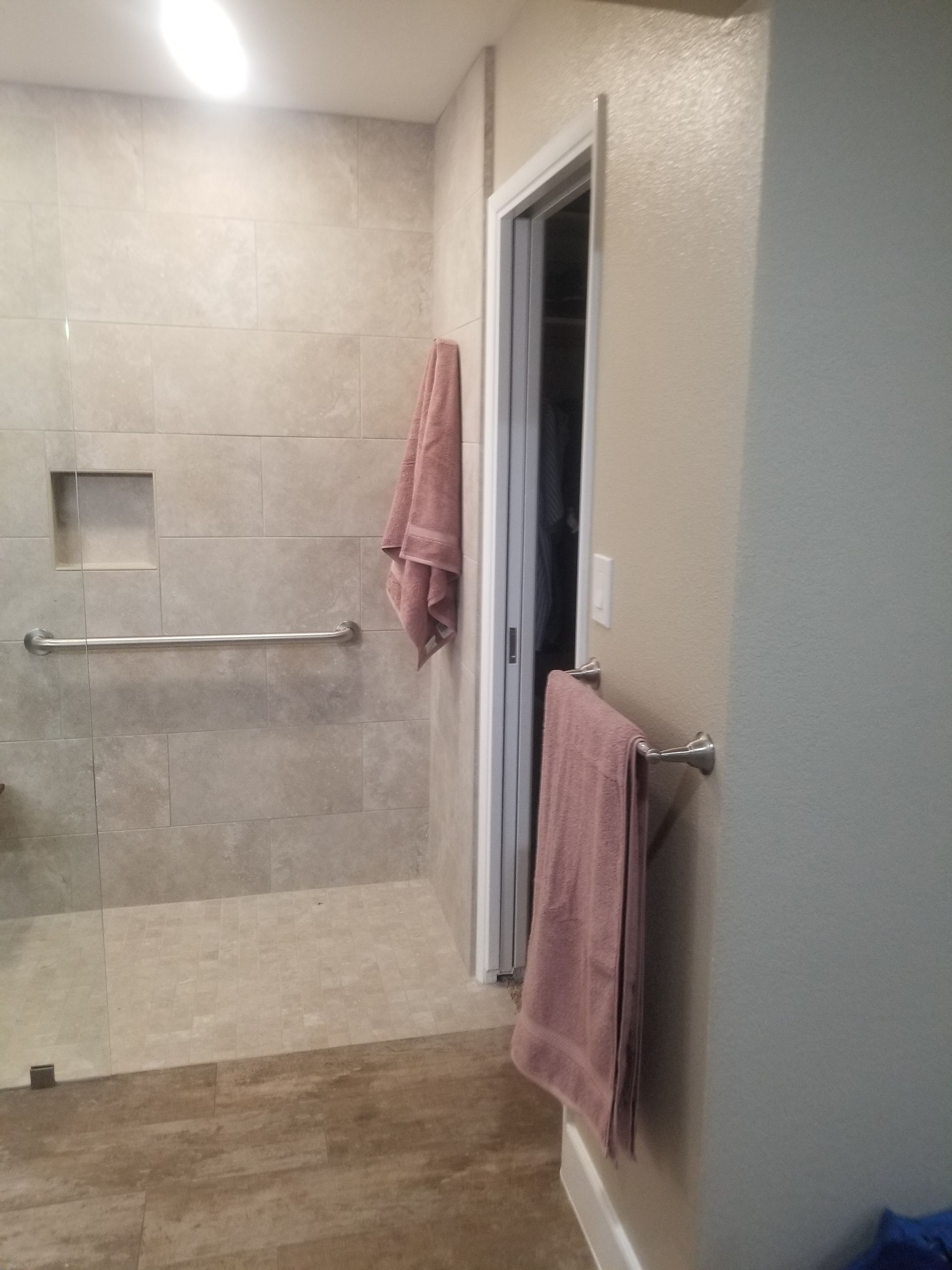 A bathroom with a walk in shower and a towel rack.