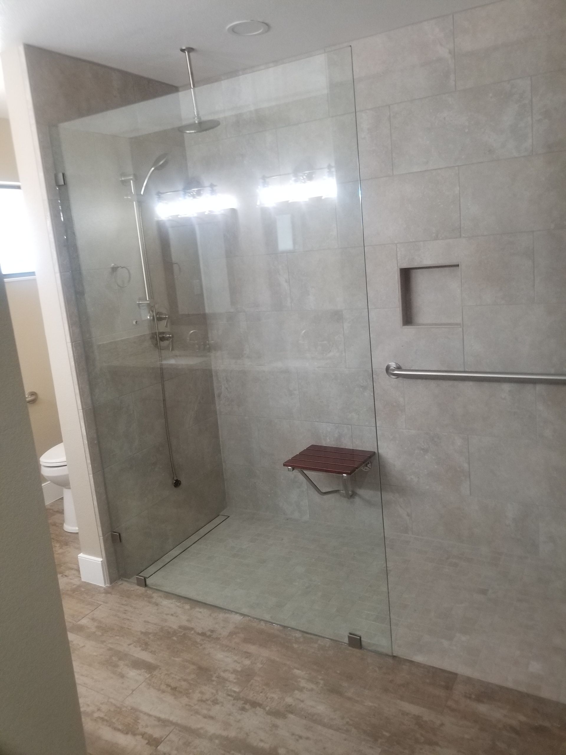 A bathroom with a walk in shower with a glass door.