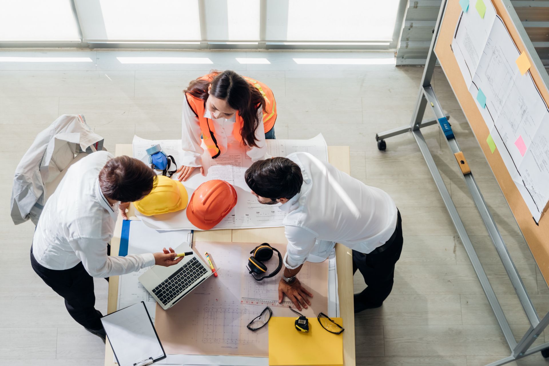 A group of people are sitting around a table with hard hats and a laptop.