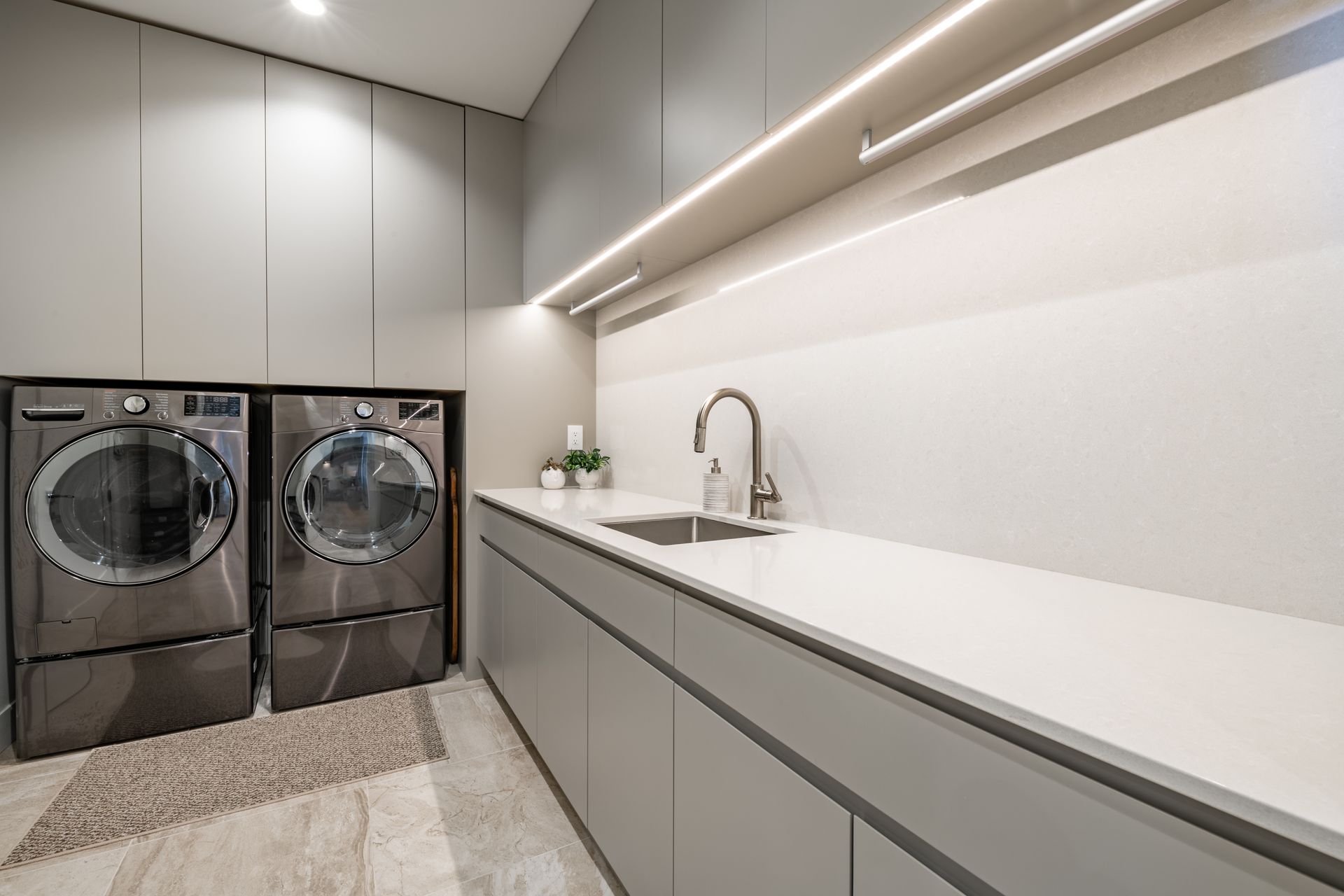 A laundry room with two washers and dryers and a sink.
