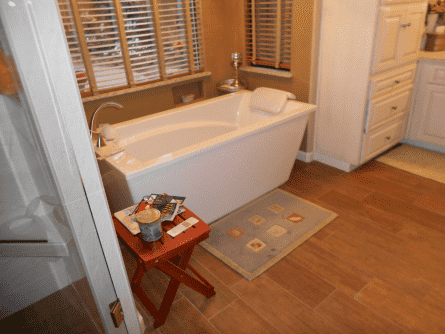 A bathroom with a bathtub and a wooden floor