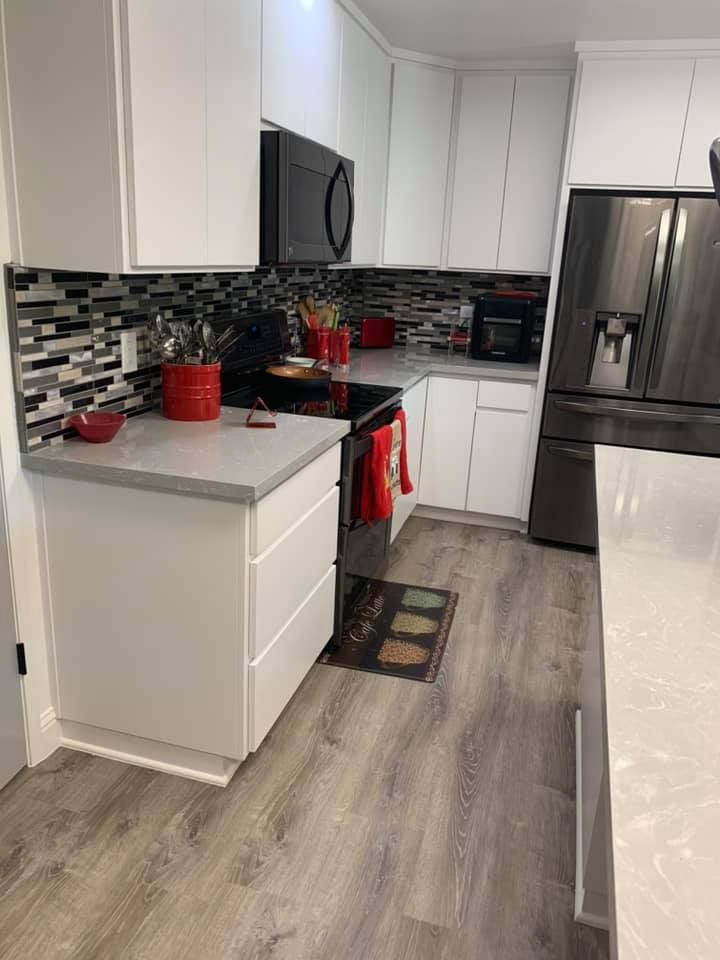 A kitchen with white cabinets , a stove , a refrigerator , and a microwave.
