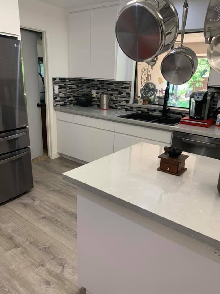 A kitchen with pots and pans hanging from the ceiling and a white counter top.