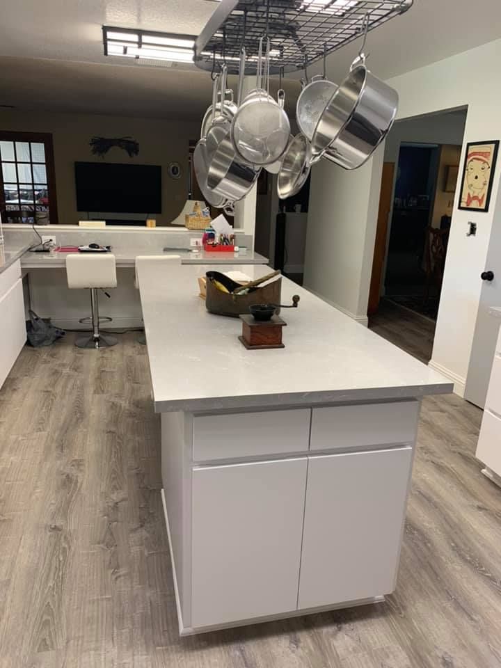A kitchen with a large island and pots and pans hanging from the ceiling.