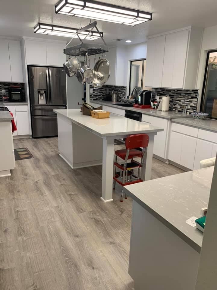 A kitchen with white cabinets , stainless steel appliances , and a large island.
