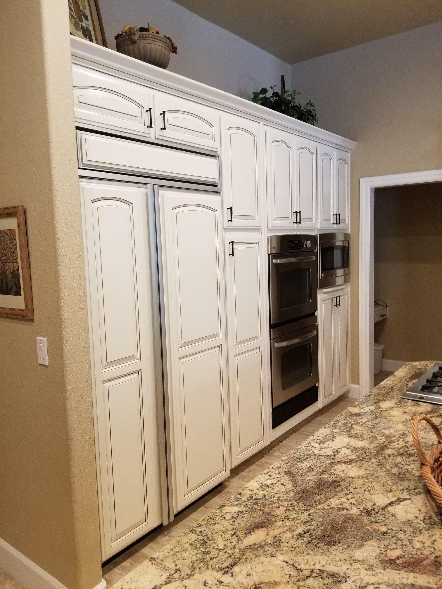 A kitchen with white cabinets , granite counter tops , and stainless steel appliances.