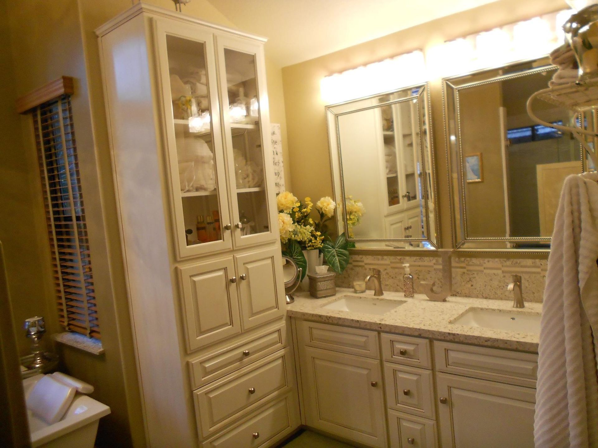 A bathroom with two sinks , a large cabinet , a mirror and a window.