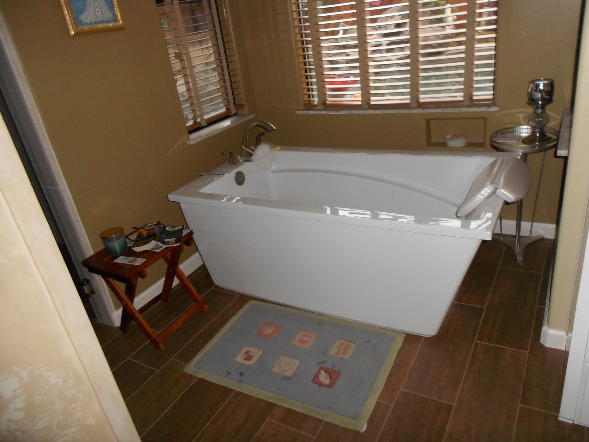 A bathtub in a bathroom next to a window with blinds