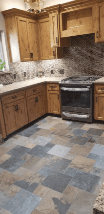 A kitchen with wooden cabinets , a stove , and a tile floor.