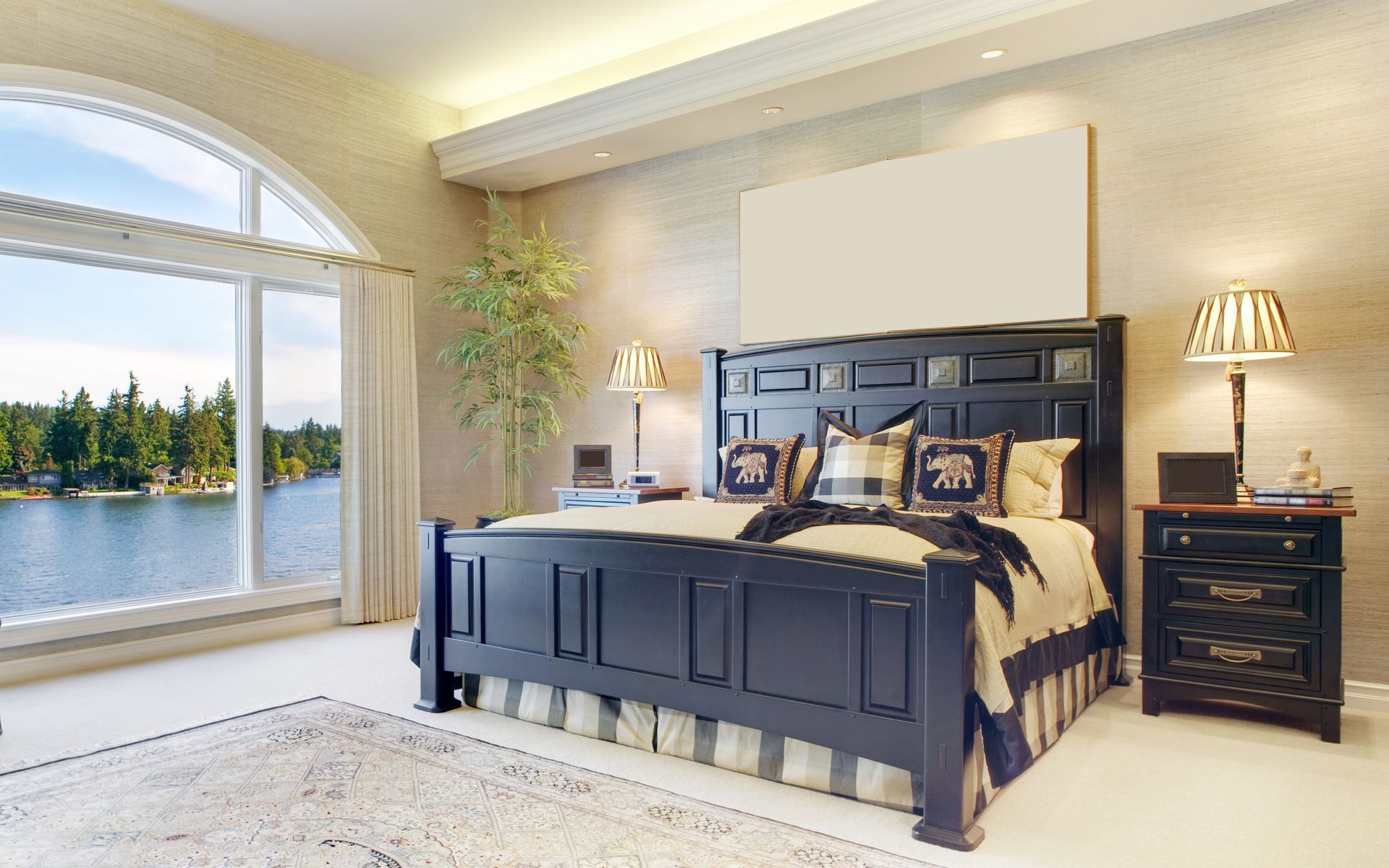 A bedroom with a large bed and a large window overlooking a lake.