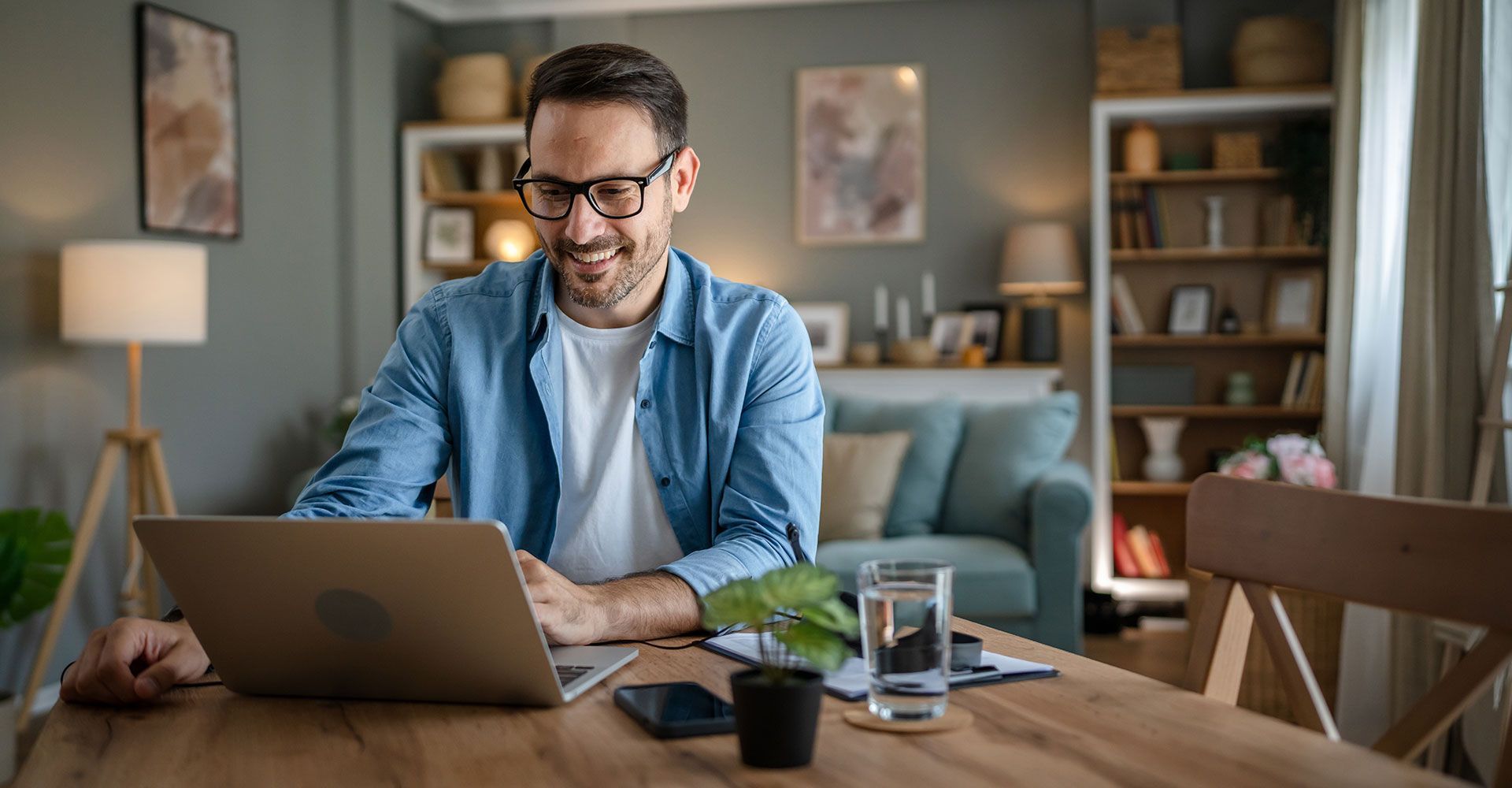 A man is sitting at a table using a laptop computer.