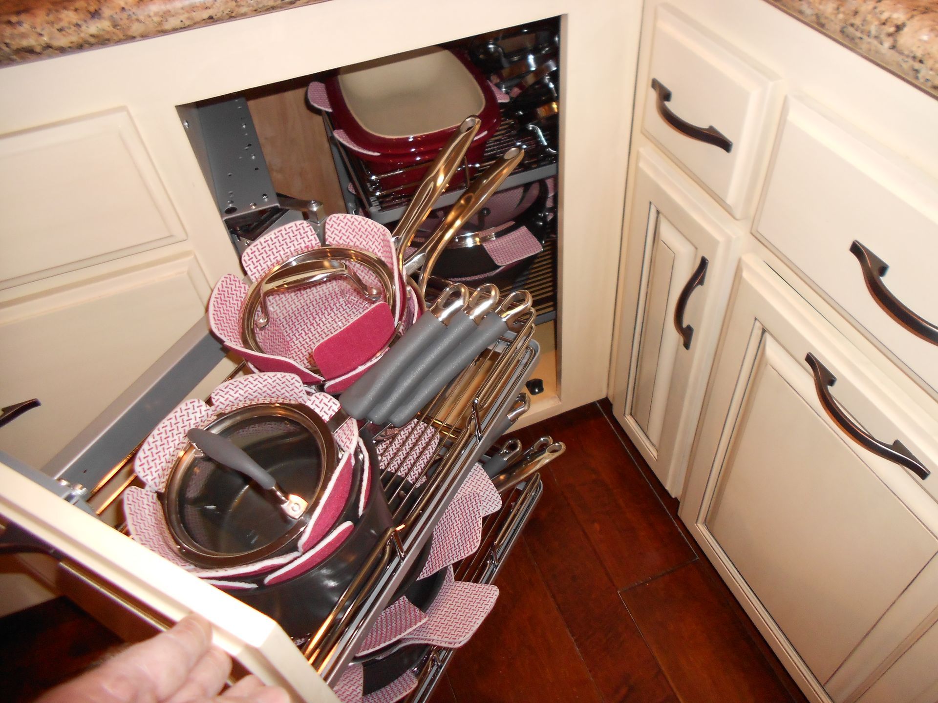 A person is reaching into a drawer filled with pots and pans