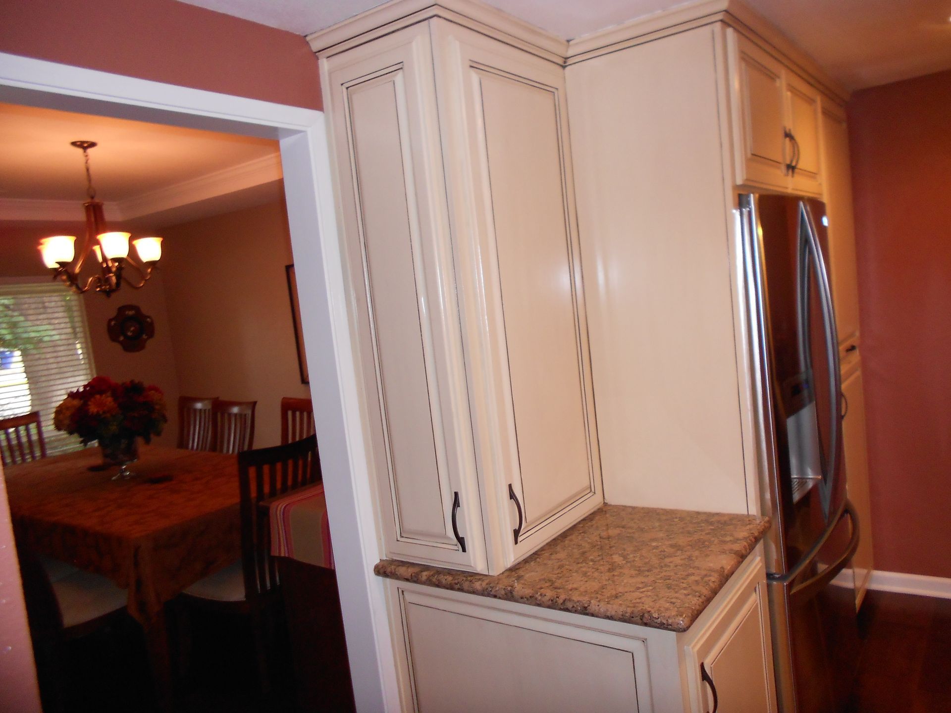 A kitchen with white cabinets and a stainless steel refrigerator