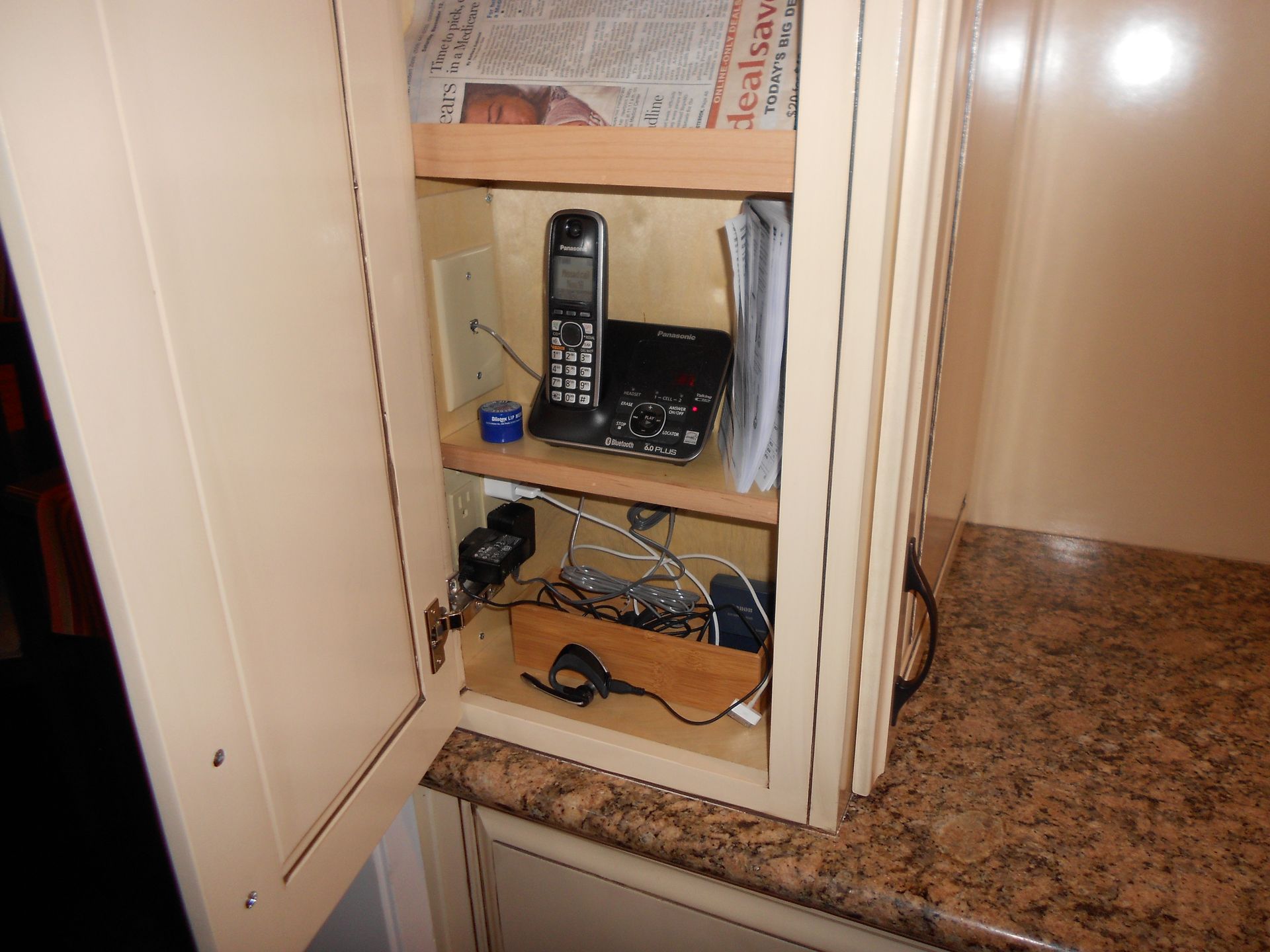 A phone sits on a shelf in a cabinet with the door open