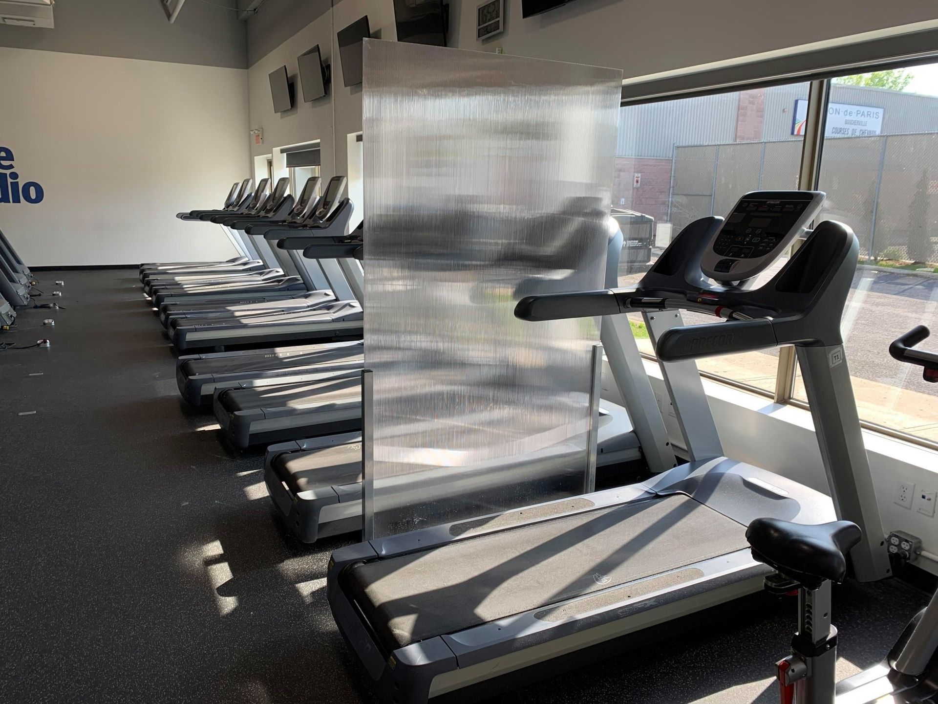 A row of treadmills are lined up in a gym.