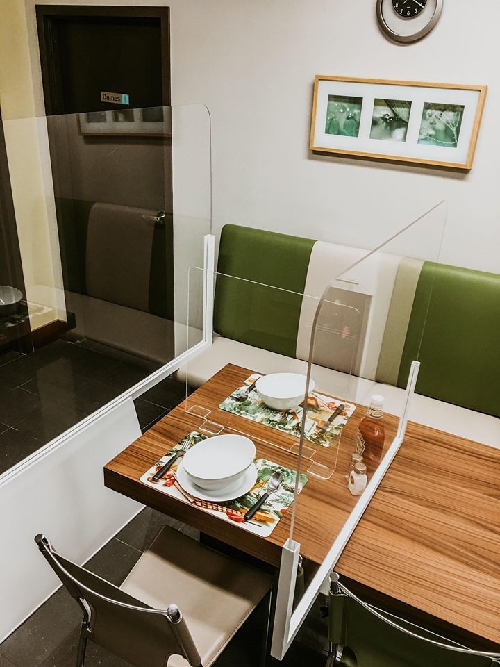 A dining room with a table and chairs and a divider between the table and the bench.