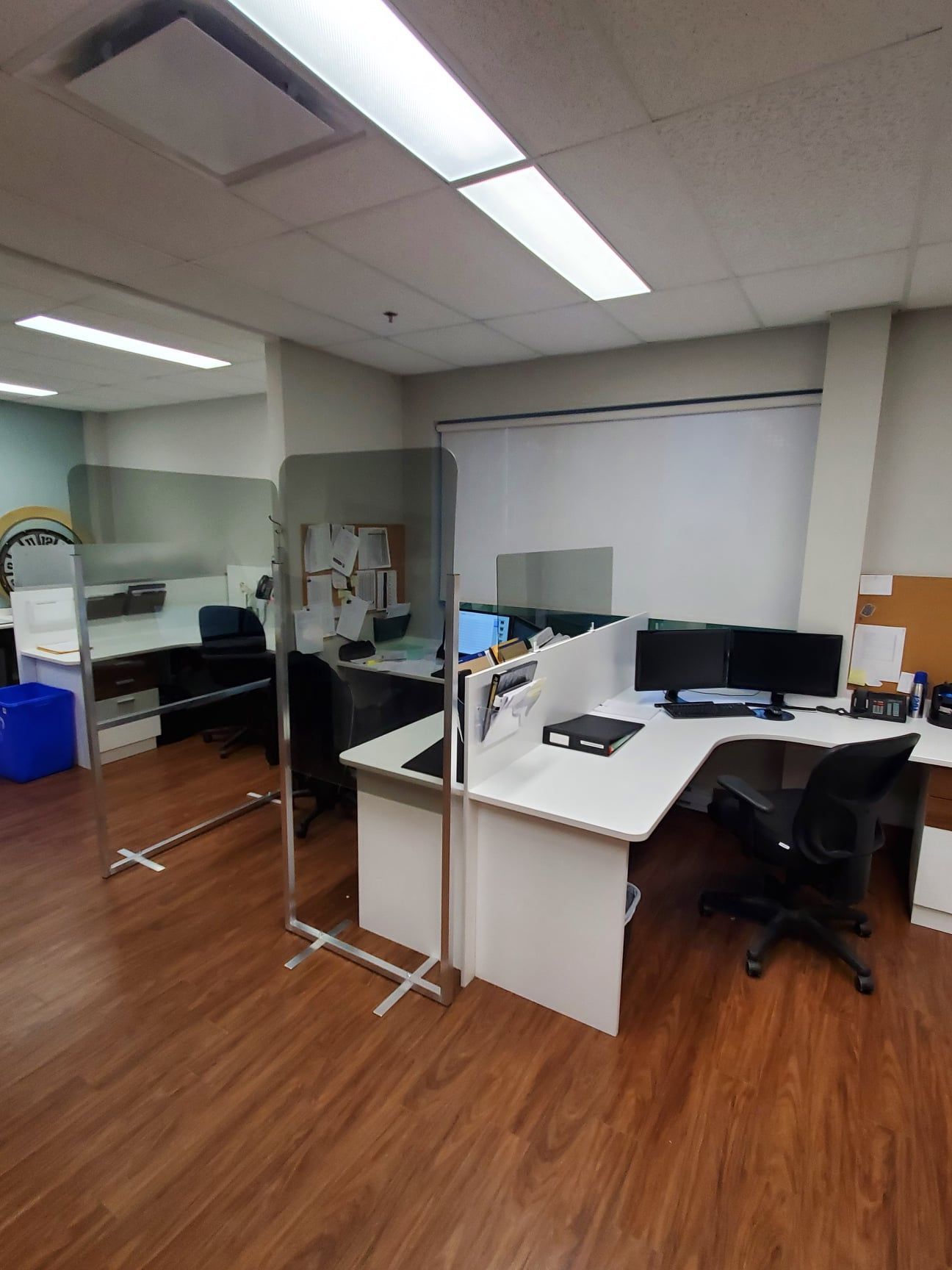 A room with a desk , chairs , computers and a glass wall.