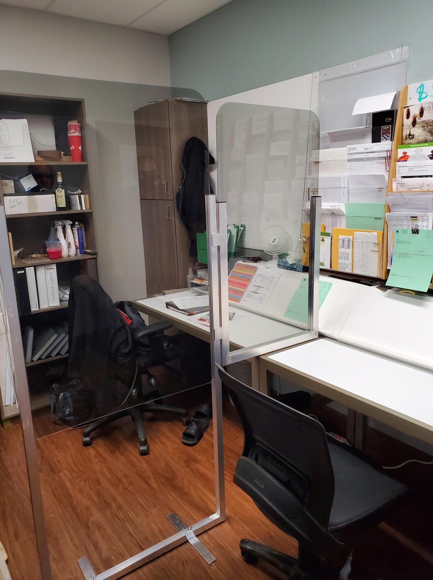 A room with a desk , chair , shelves and a divider.