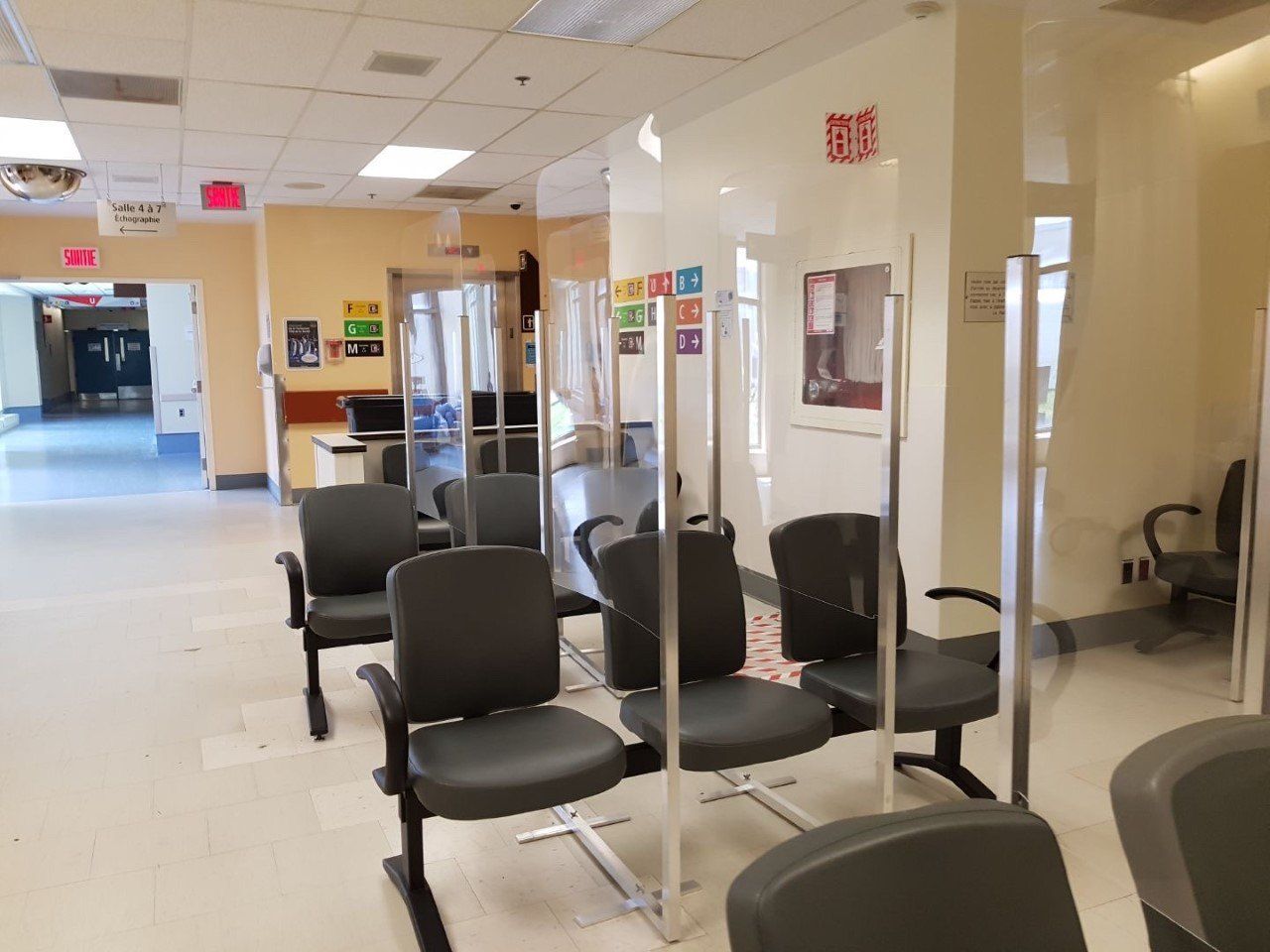 A waiting room in a hospital with chairs and a glass wall.