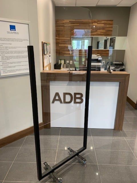 A glass barrier in front of a counter that says adb