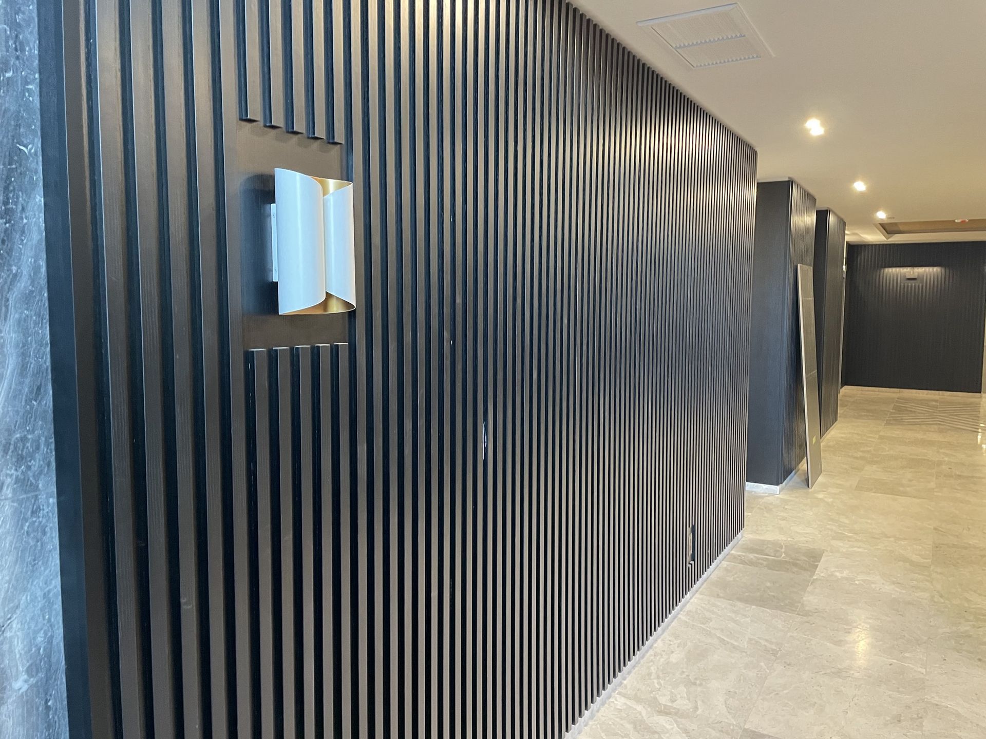 A hallway with a black wall and a light on the wall.