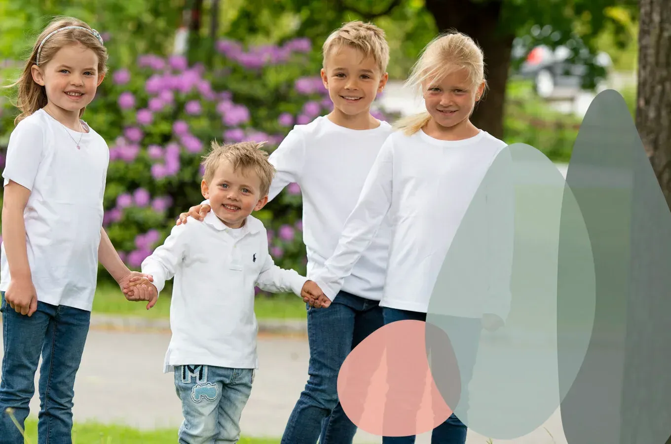 Fire barn i hvite skjorter og blå jeans holder hender mens de går sammen i en grønn park med lilla blomster.