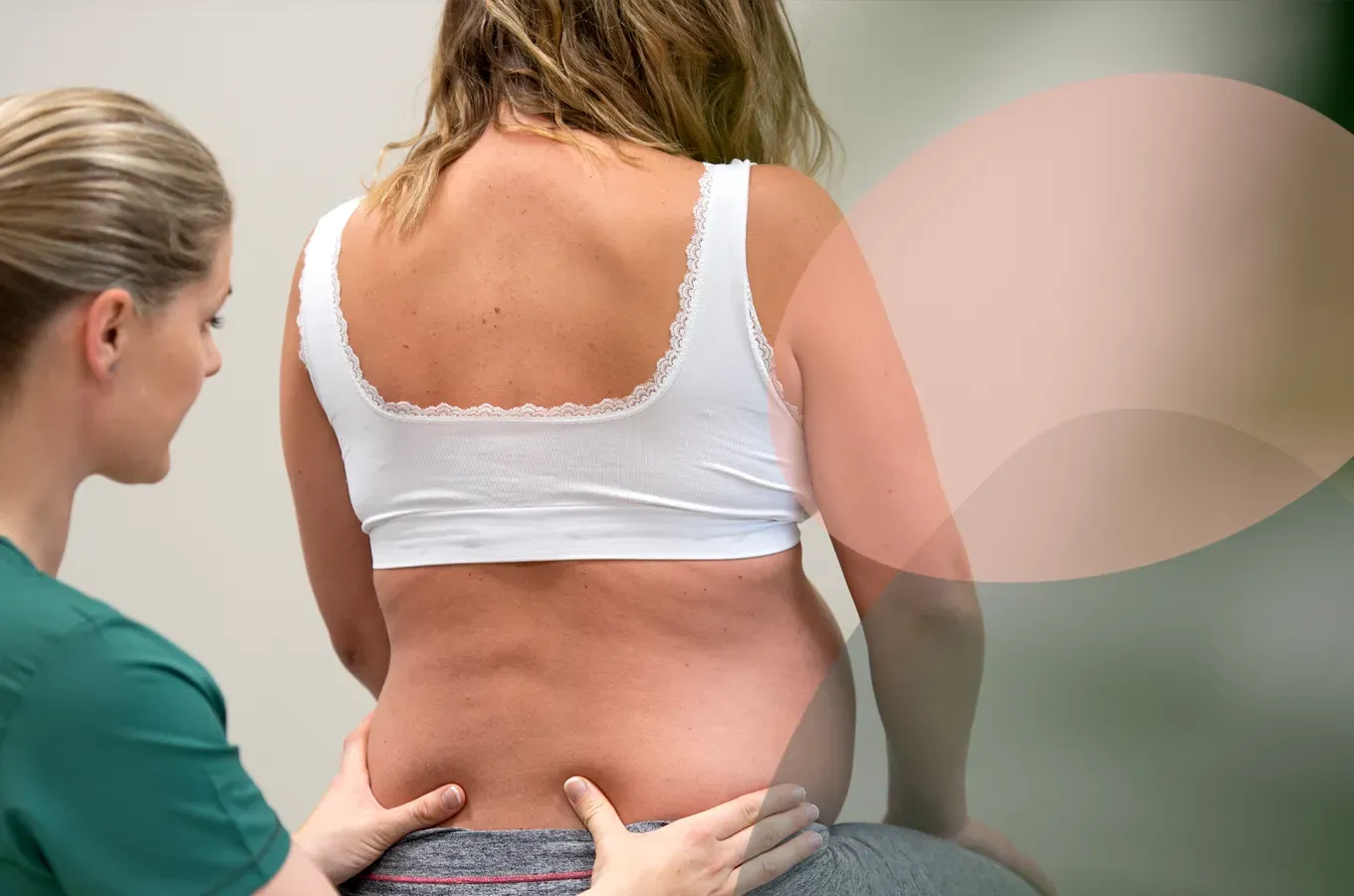 En medisinsk fagperson i en grønn topp undersøker en pasients korsrygg.